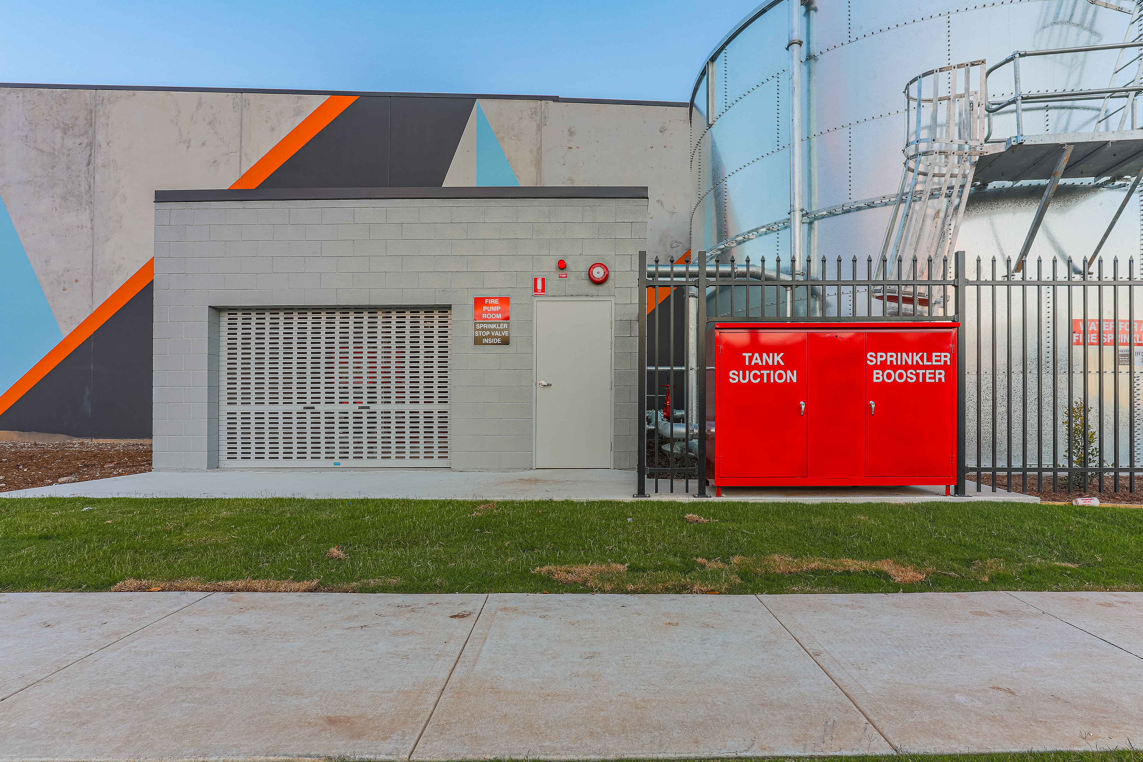 Industrial facility featuring a prominently displayed fire sprinkler booster and modern architectural elements, designed for safety and functionality, located in Brisbane, QLD. Professional commercial photography by Jeremy Murphy.