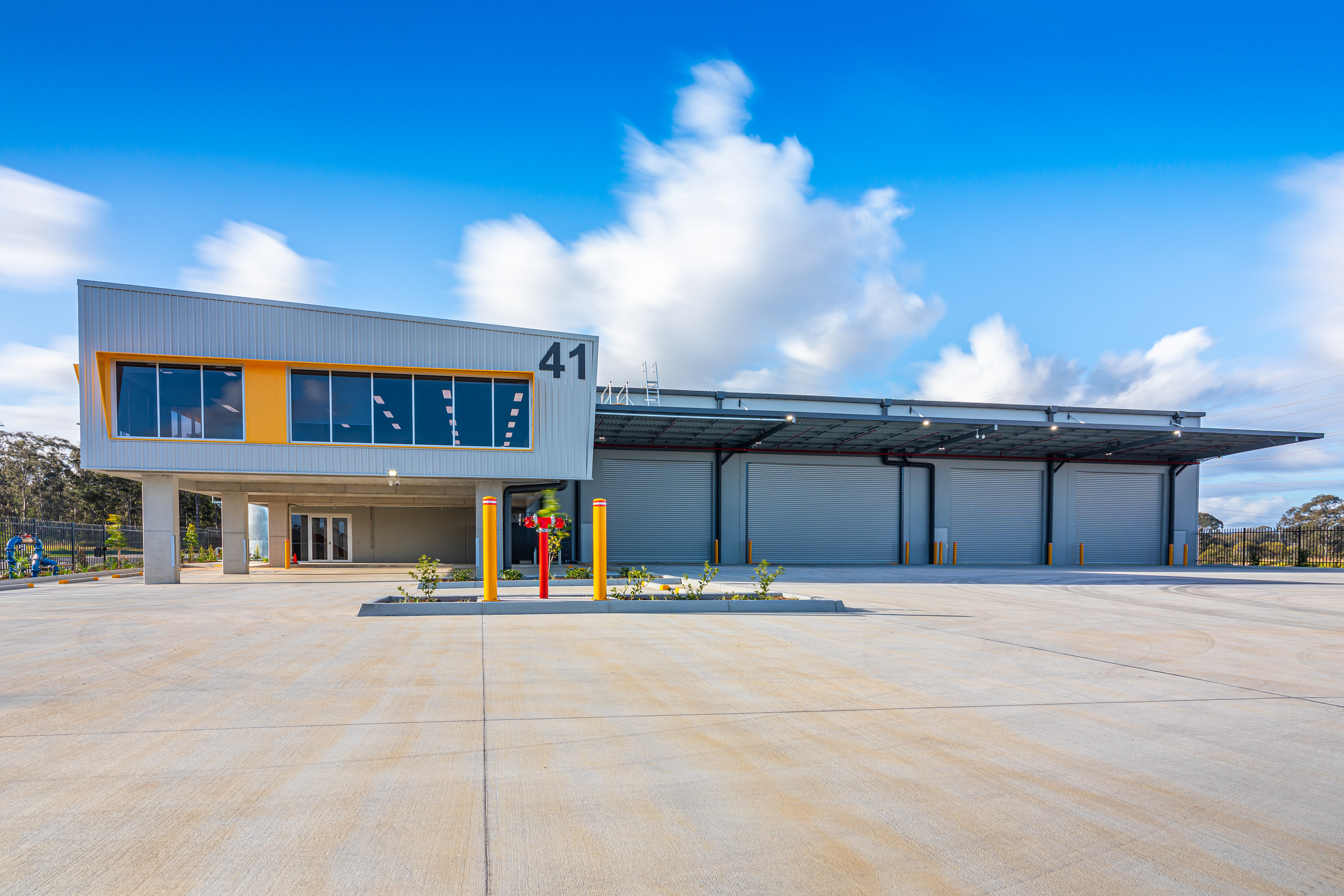 Modern industrial facility with expansive outdoor area and sleek architectural design, featuring a large office space and multiple roller doors, located in Ipswich, QLD. Professional commercial photography by Jeremy Murphy.