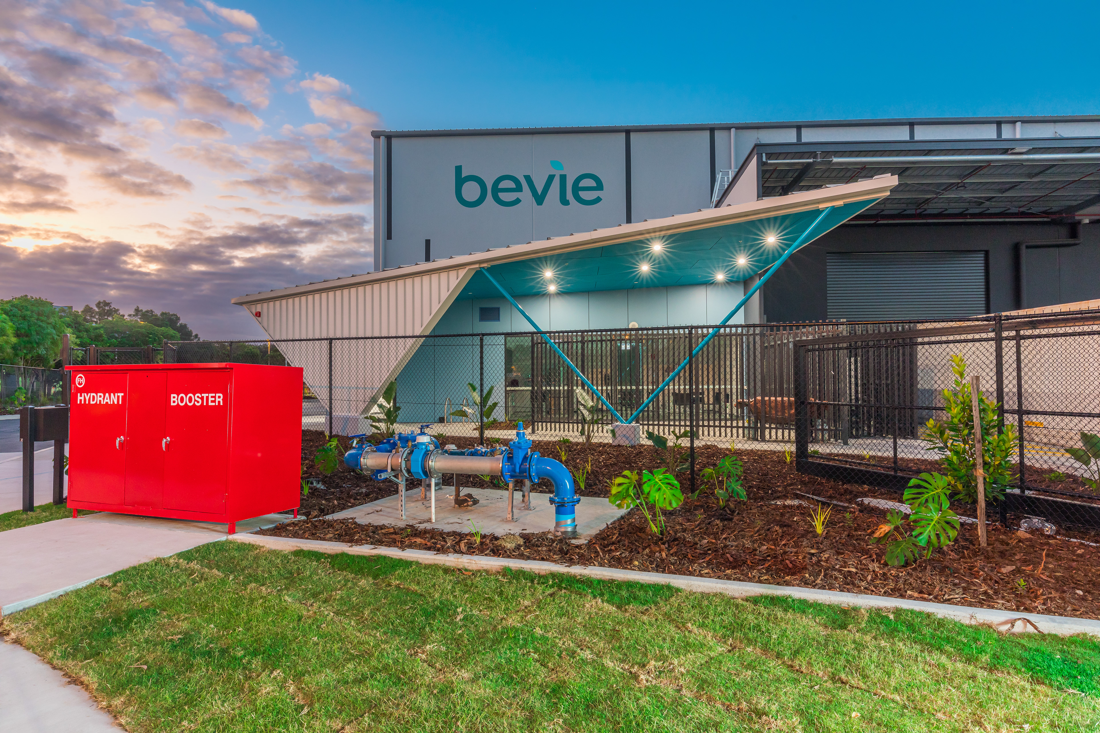Bevie industrial facility with contemporary design, landscaped entrance, and prominent hydrant booster, showcasing modern infrastructure, located in Brisbane, QLD. Professional commercial photography by Jeremy Murphy.