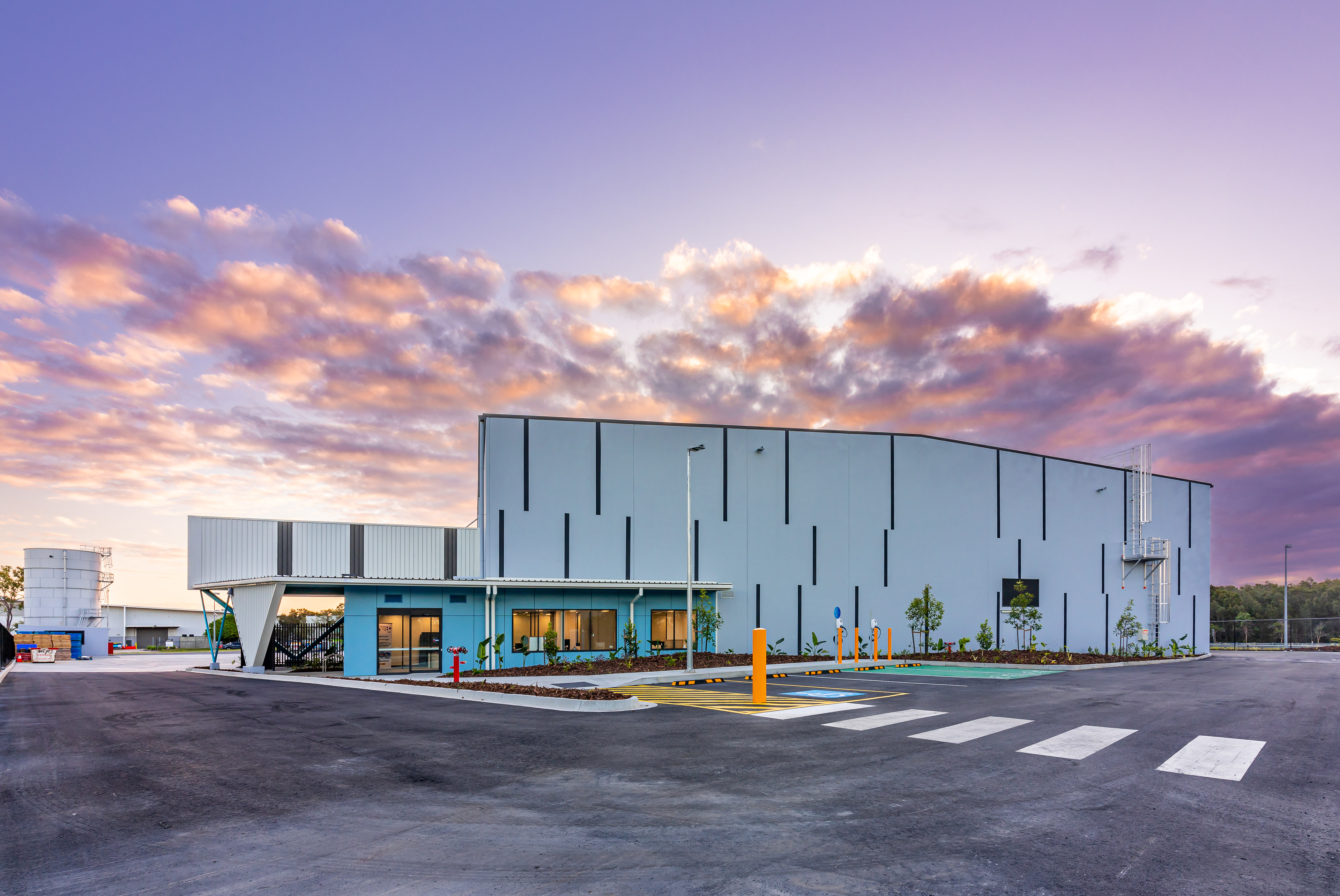 Contemporary warehouse facility with a unique architectural design and ample parking space, showcased during a stunning sunset, located in Ipswich, QLD. Professional commercial photography by Jeremy Murphy.