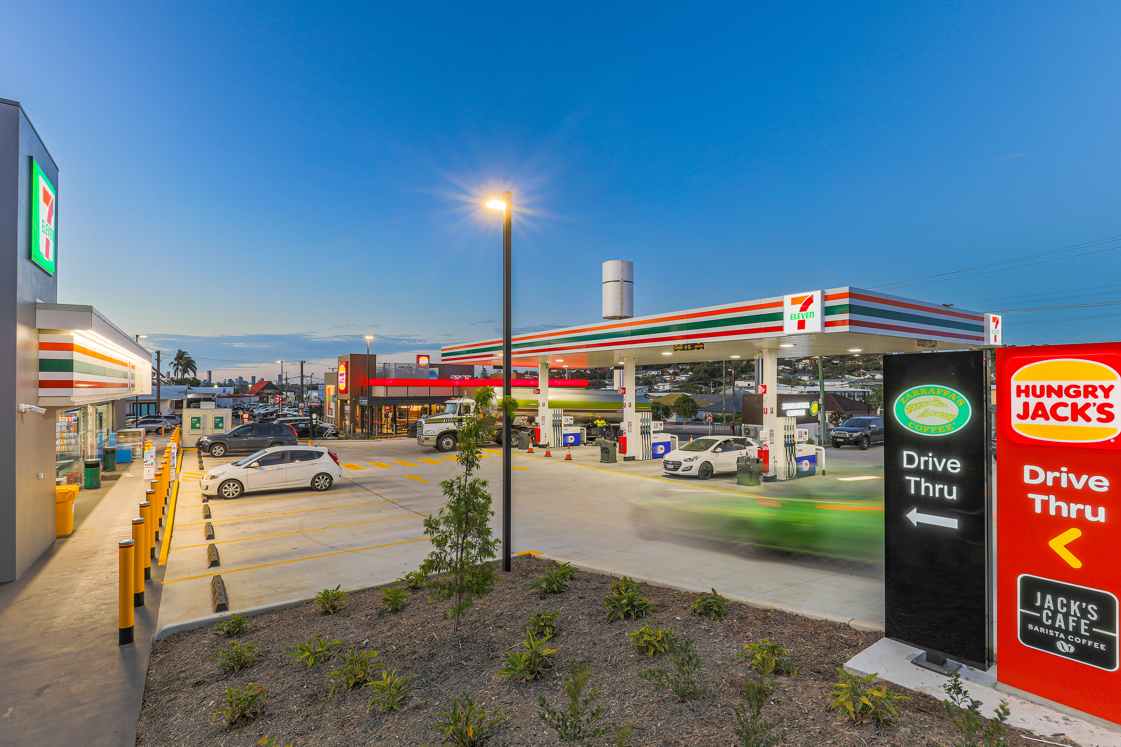 7-Eleven gas station with a drive-thru for Zarraffa's Coffee and Hungry Jack's, providing convenience and modern amenities, located in Ipswich, QLD. Professional commercial photography by Jeremy Murphy.