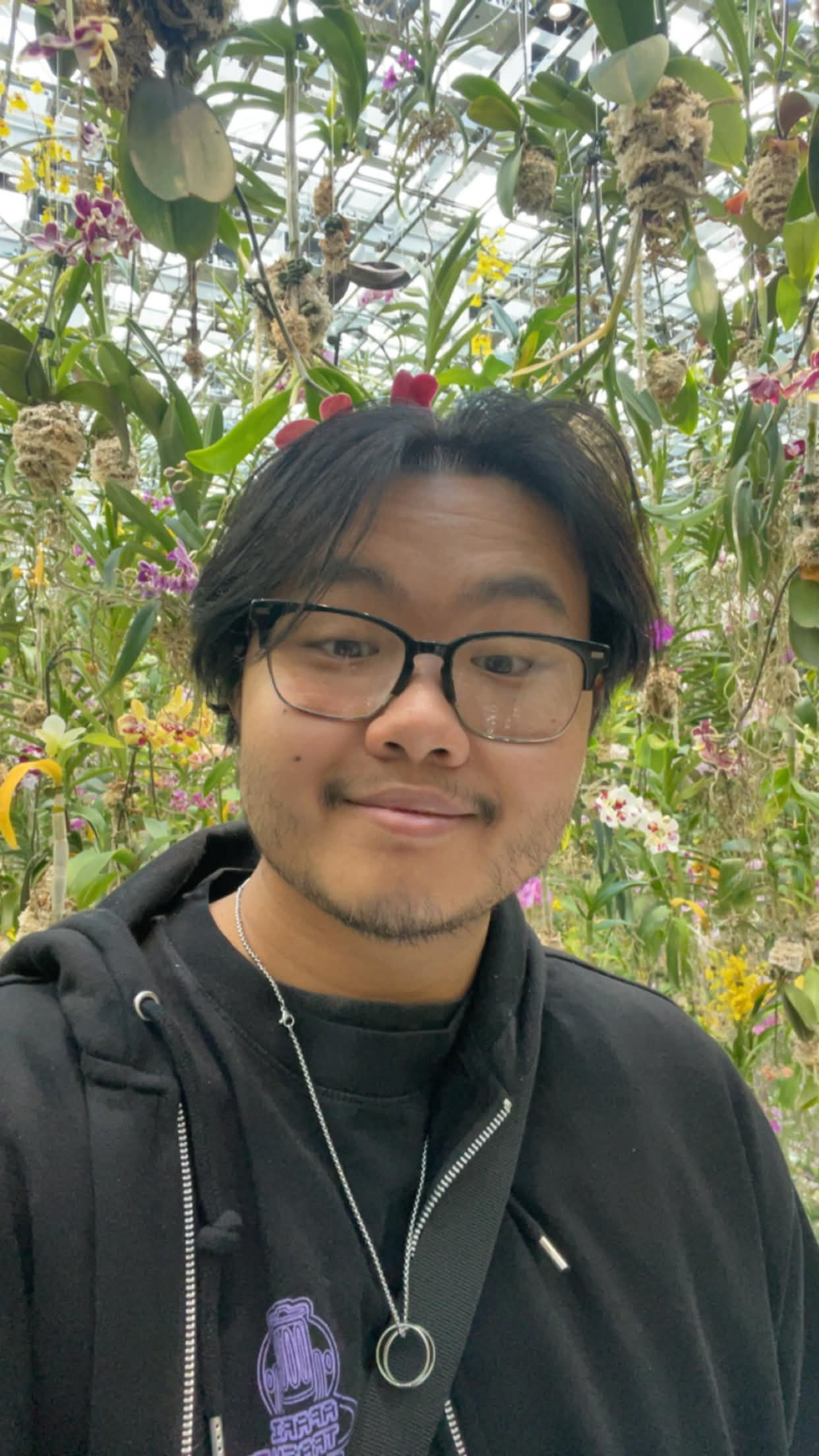 A selfie of Evan looking into the camera in front of a garden