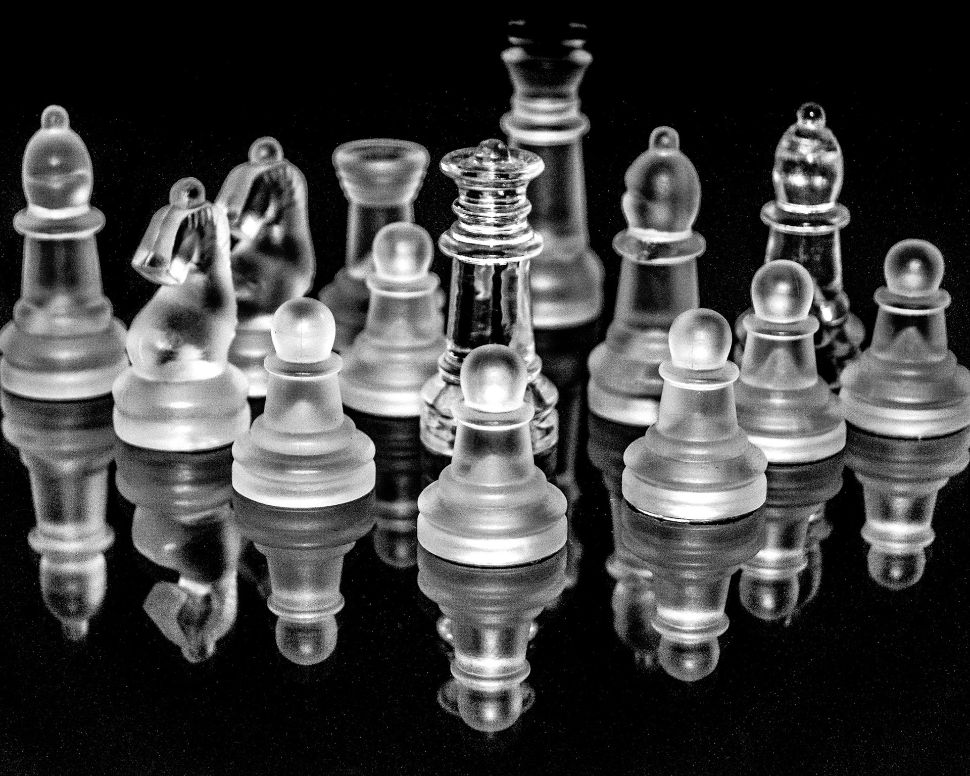 glass chess pieces arranged on reflective black surface