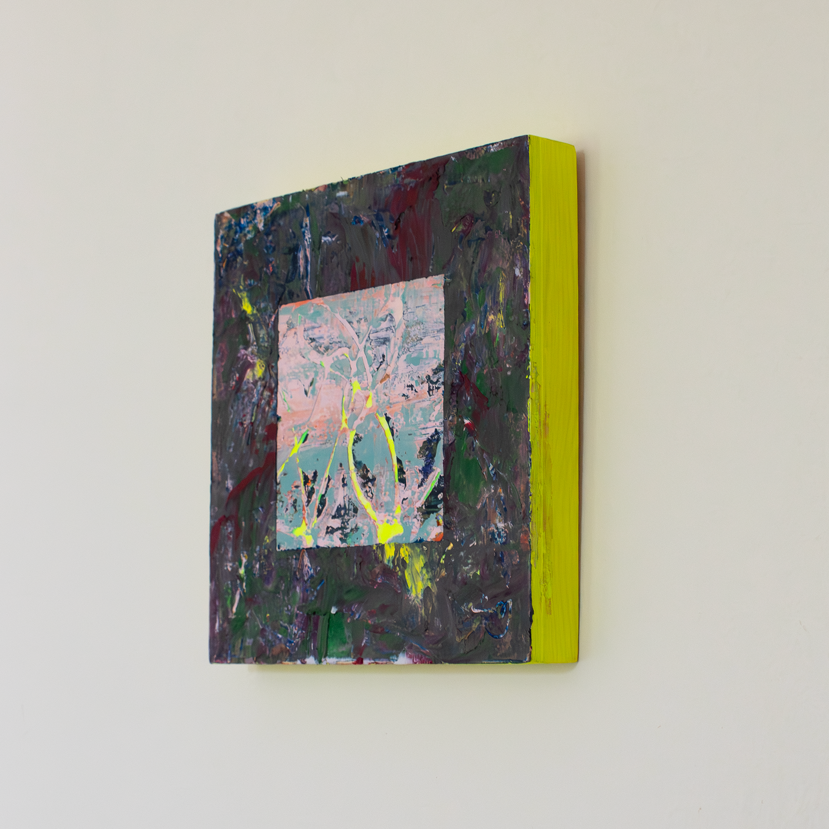 Left side view of textural abstract painting with thick impasto surface with colours of deep purple, blood red, green and yellow. In the centre there is a cut away square exposing a soft pink and blue textural underpainting with some thin areas of neon yellow peaking through. The edges of the painting are neon yellow and make a soft yellow glow against the while wall.