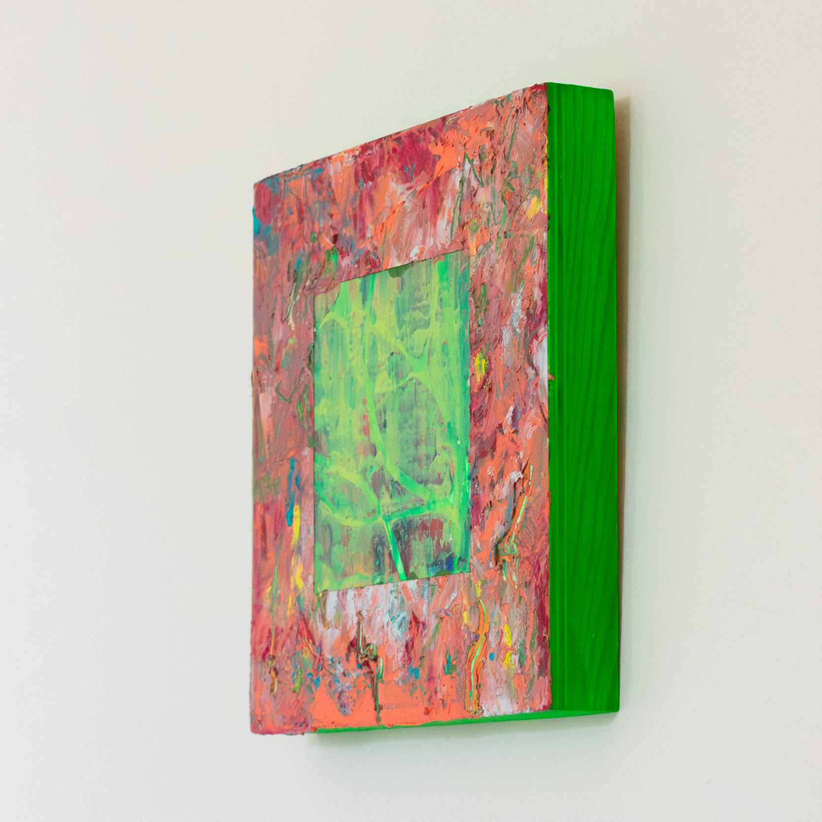 Right side view of textural abstract painting with thick impasto surface with colours of peach, orange, red and yellow. In the centre there is a cut away square exposing a green and yellow textural underpainting. The edges of the painting are neon green.