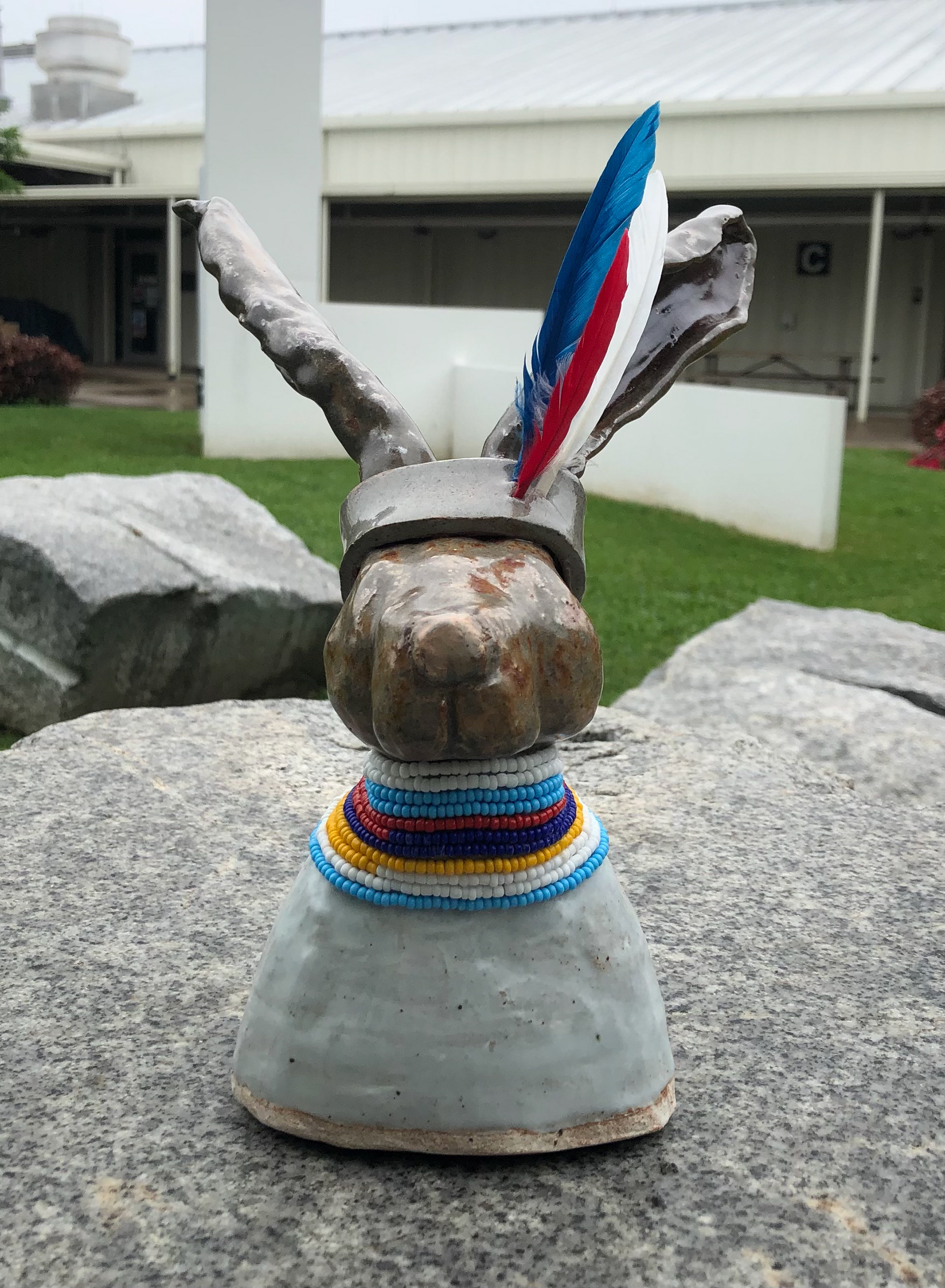 High fire clay embellished with glass beads and feathers.