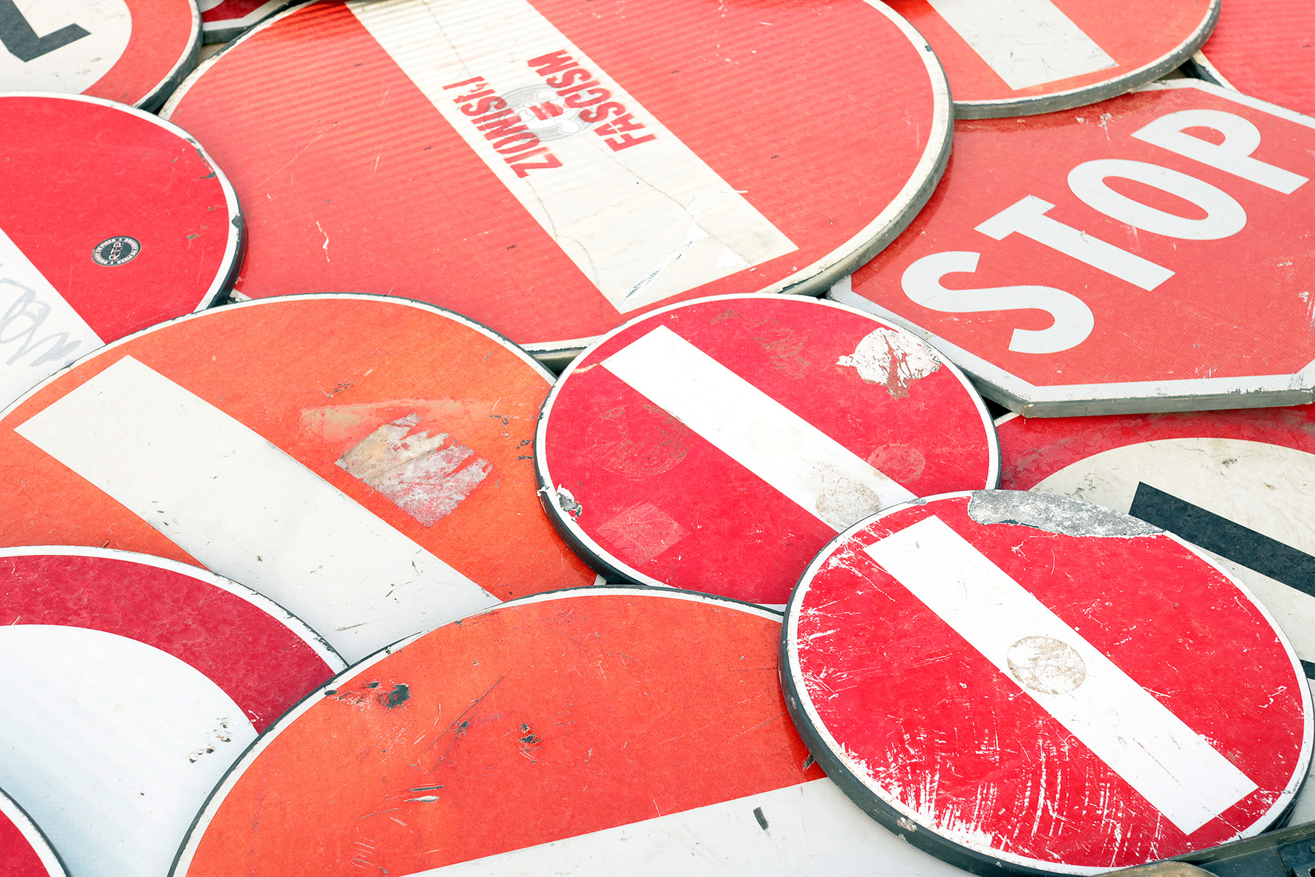 Close-up of overlapping red and white road signs in Concerto 0 by Scoobafish, showing scratches, faded surfaces and traces of previous use.