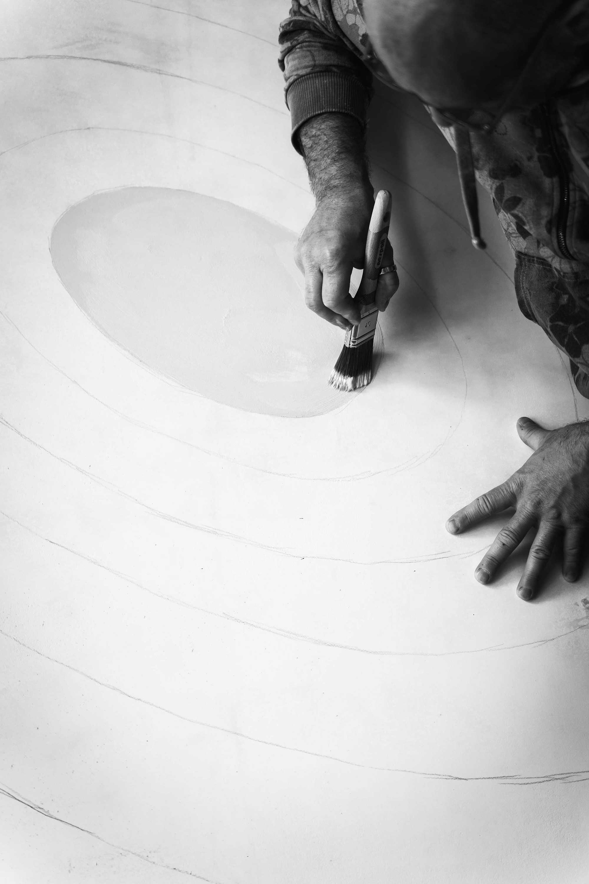 Detail of artist painting circular forms with brush - recycled plastic fish sculpture creation process