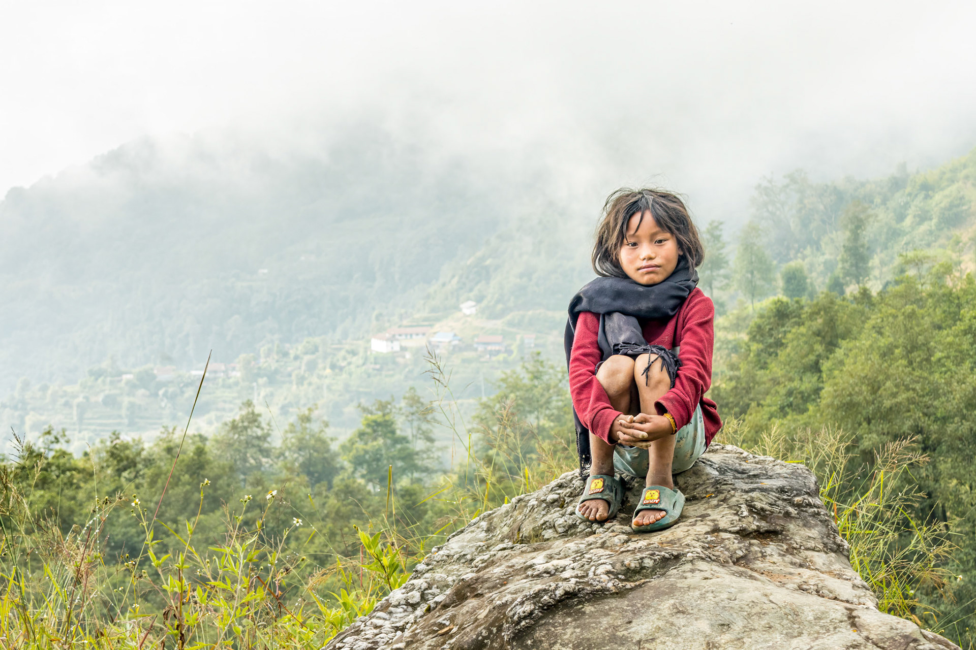 High up in the Himalayan foothills, on our way to Kanchenjunga Base Camp, we passed this little girl, sat alone in the stunning landscape nonchalantly watching us trek by