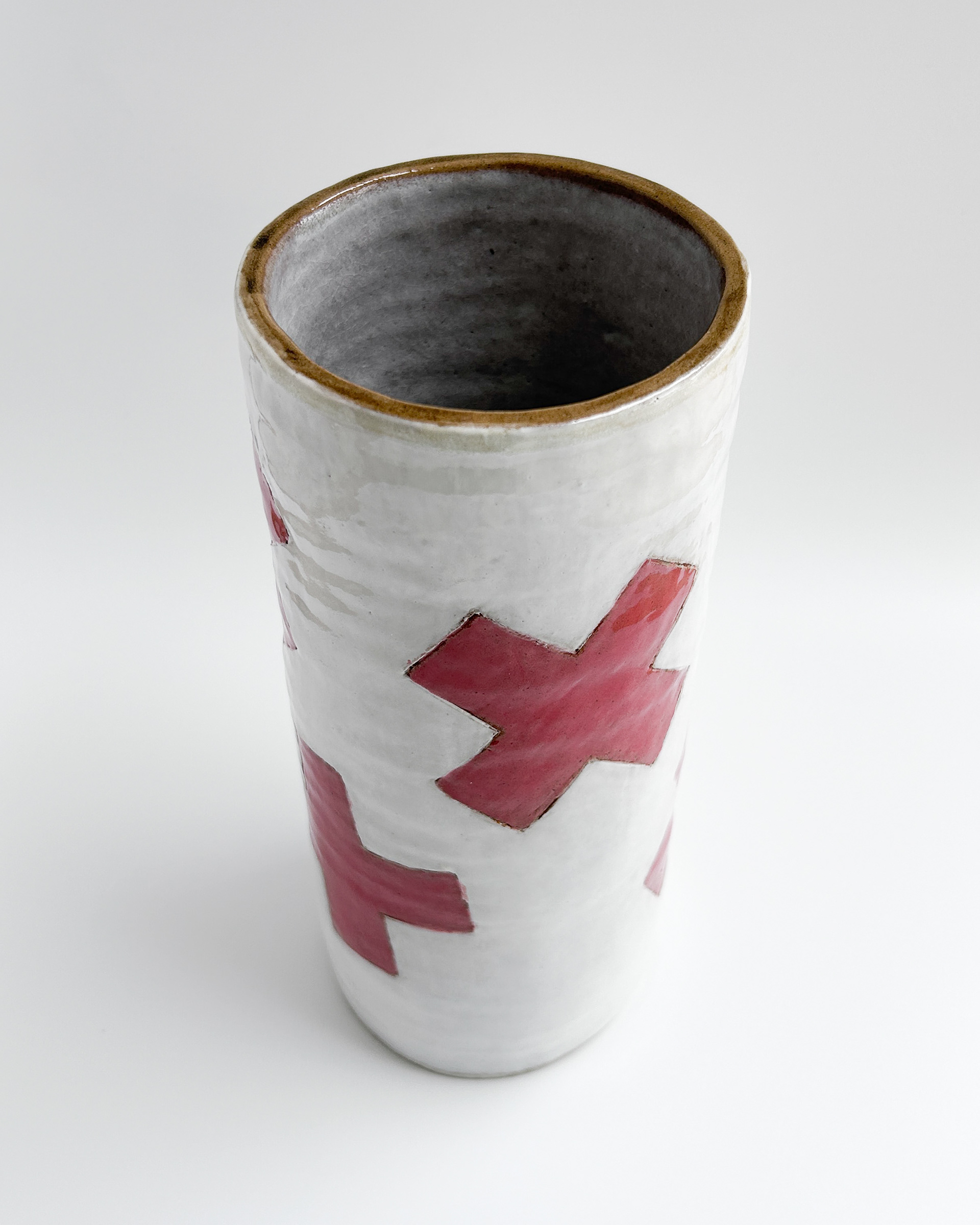 White cylindrical jar with scattered red plus symbols in glazed ceramic