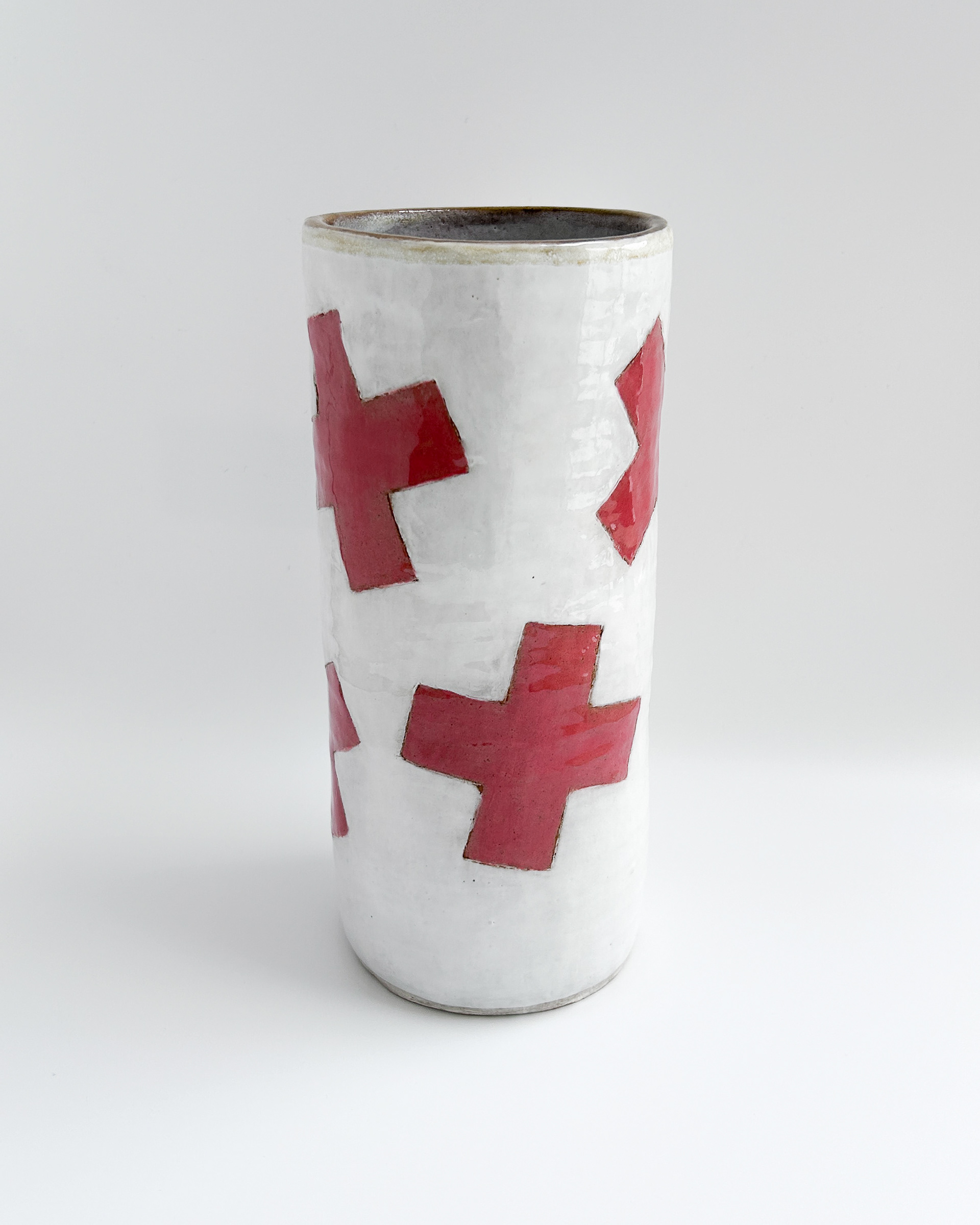 White cylindrical jar with scattered red plus symbols in glazed ceramic