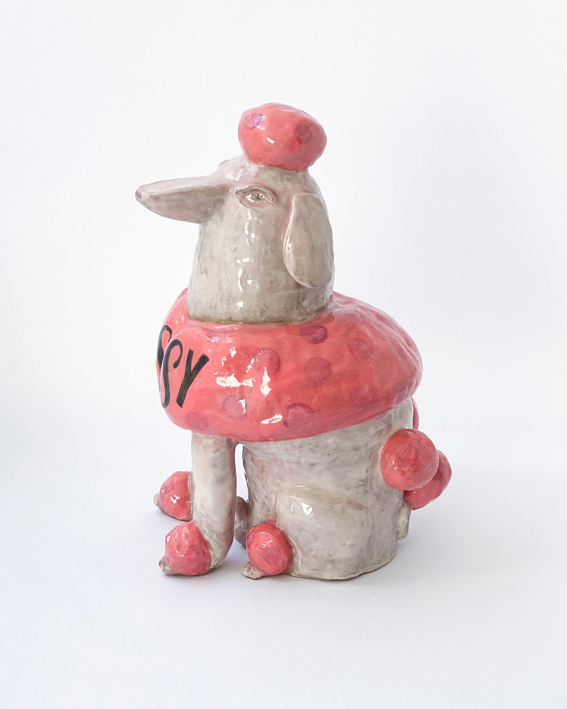 Pink and white glazed ceramic poodle sculpture labelled Sissy across the chest