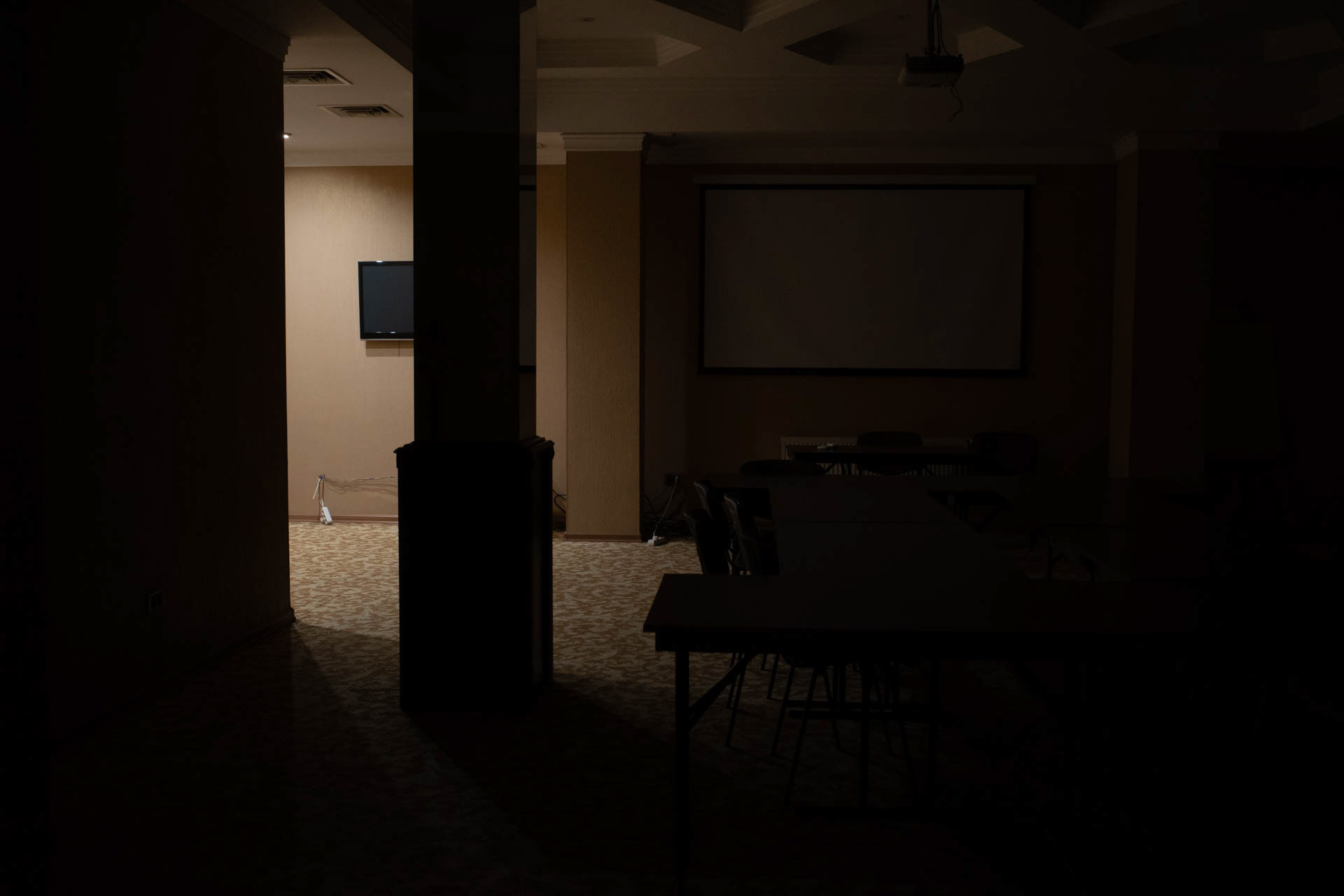A hotel conference room converted into a bomb shelter sits in darkness in Odesa, Ukraine, on June 12, 2026. The room, with its projection screen, wall-mounted television and conference tables still in place, is used as a refuge during air raid alerts.