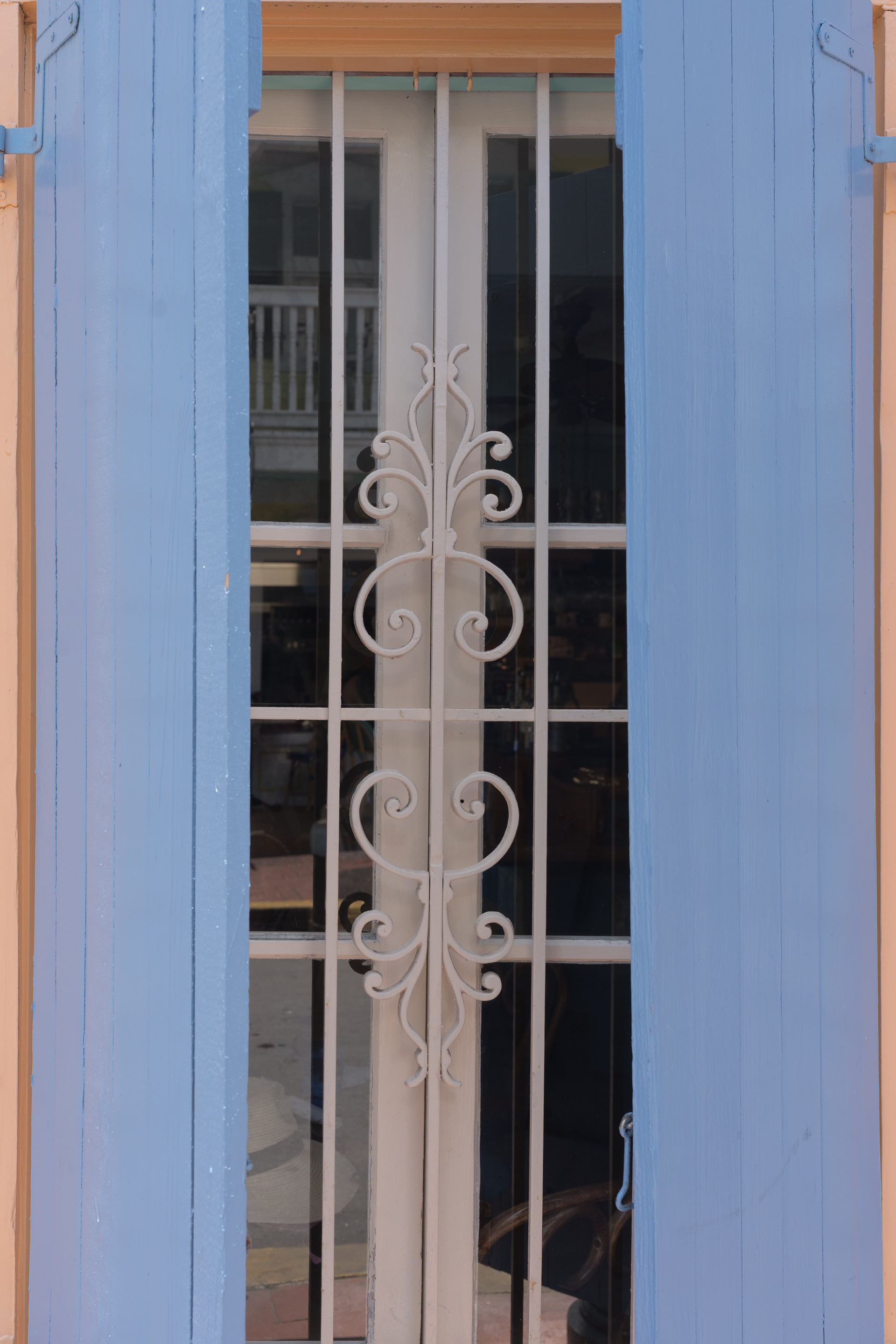 Key West 06: Blue wooden shutters around an ornate wrought-iron window in Key West