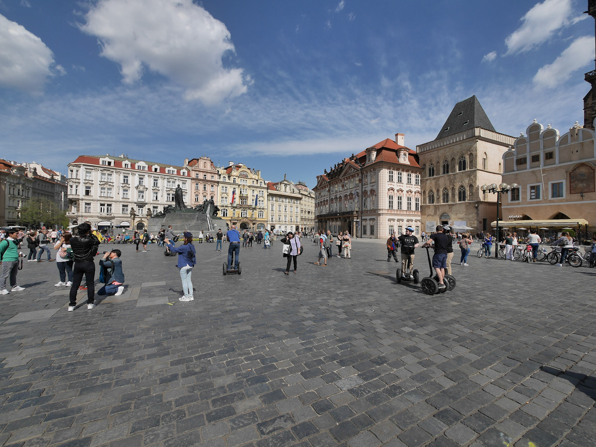 Having landed in  Prague in the morning, we decided not to waste a day getting over the jet lag and went straight to the Old Town Square. There we saw tourists (and locals) -- riding Segways, bicycles, taking pictures, etc. I bet in this picture the person walking with a phone to her ear is a local.