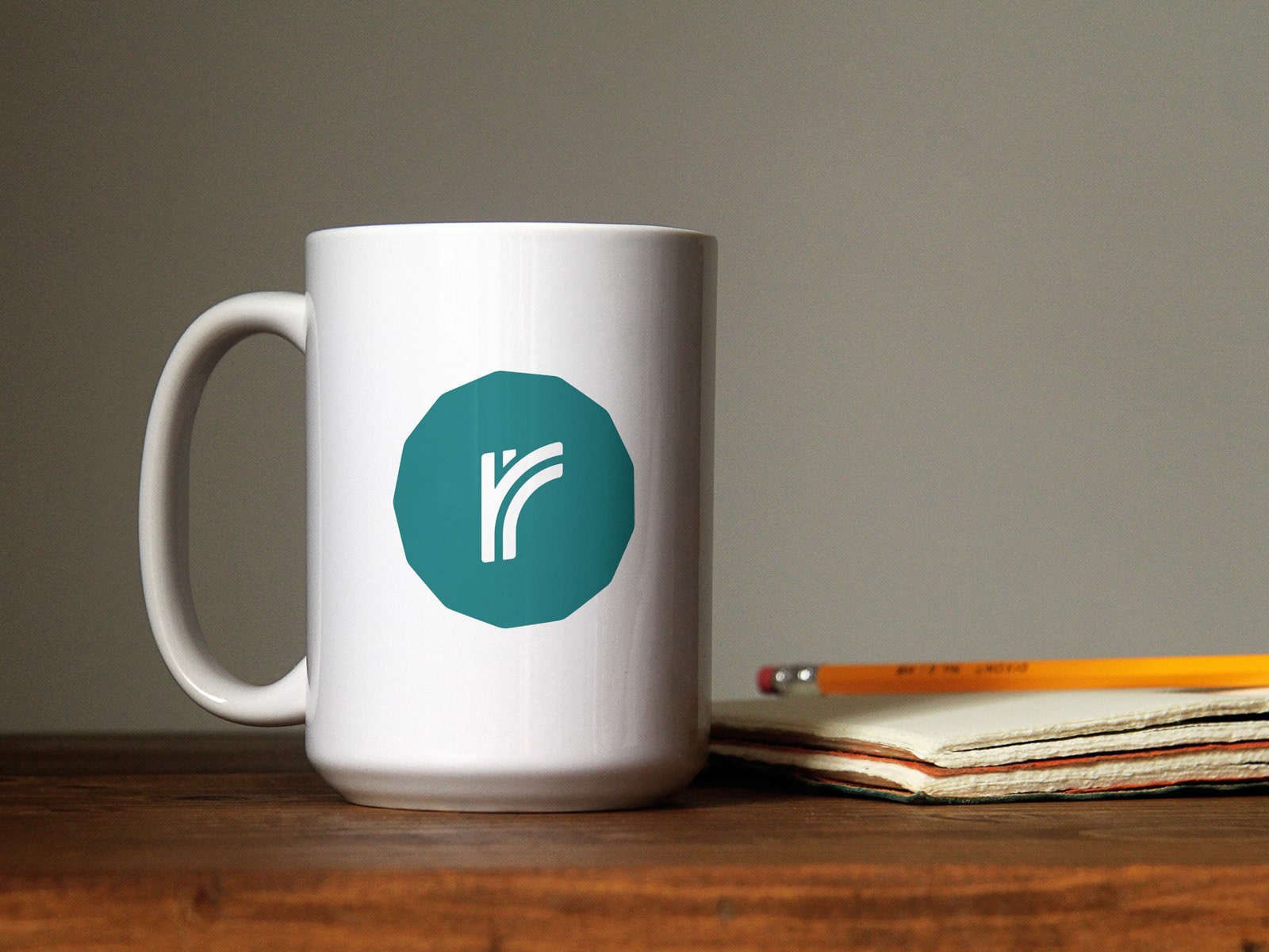 A coffee mug with an icon version of the roundhouse logo: a pair of lowercase R's resembling a railroad junction enclosed in a 13 sided shape.