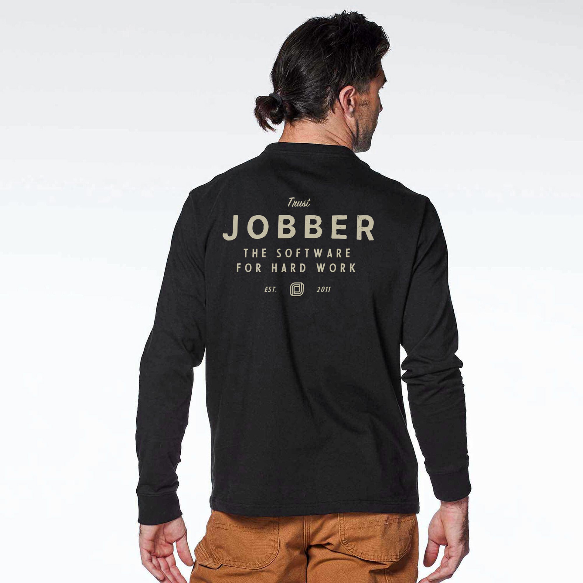 A man facing away, wearing a long sleeve shirt with "Trust Jobber, the software for hard work" in heritage style lettering.