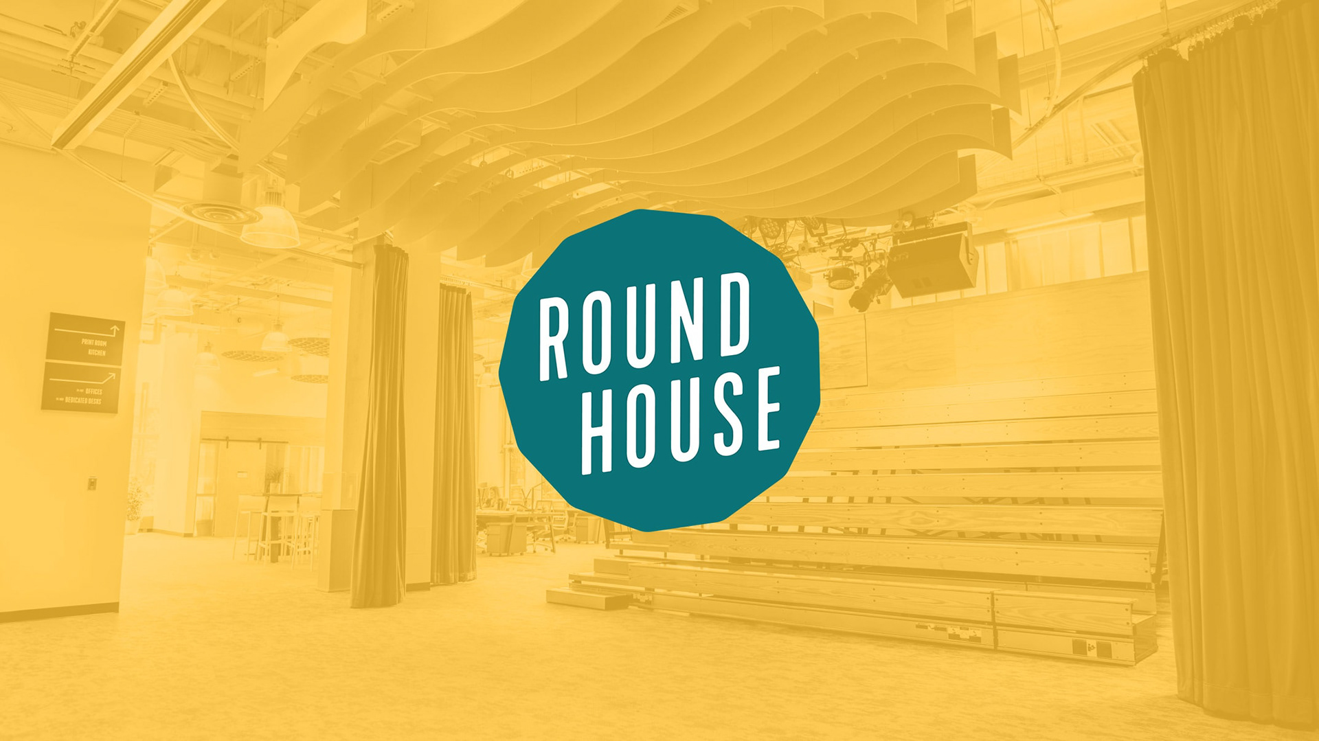 The Roundhouse logo overlayed on a photo of an event space with bleacher style seating.