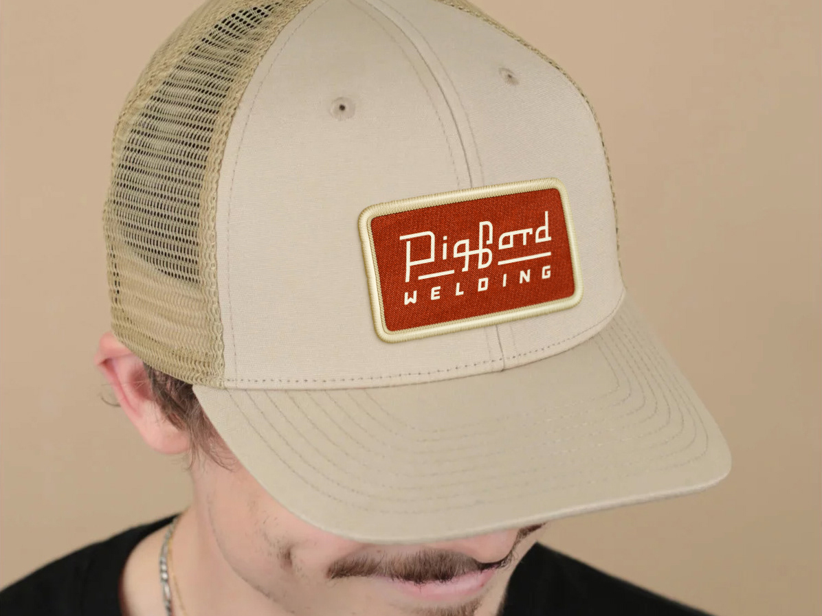 A trucker-style cap with a sewn patch of the Pigford Welding logo.