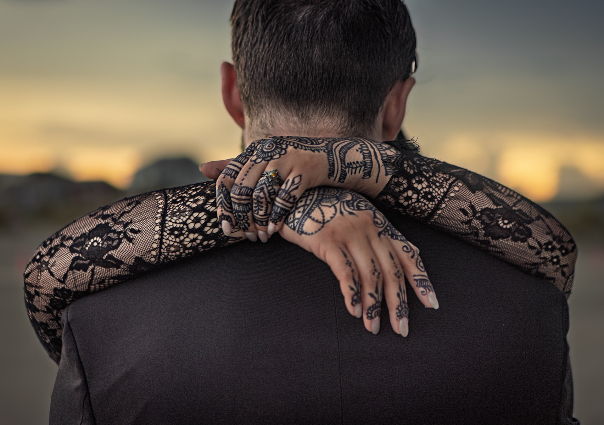Close-up of bride's hands with intricate henna tattoos embracing the groom