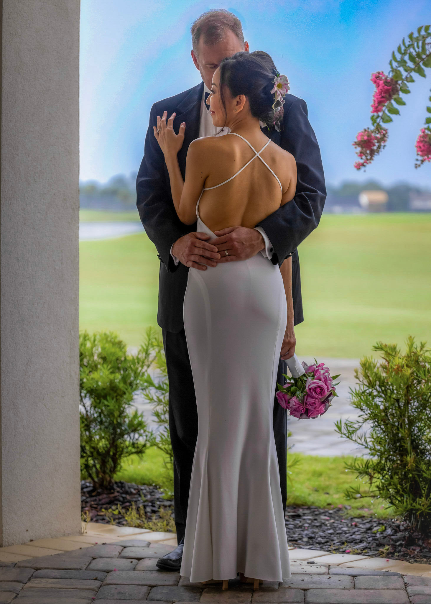 Elegant Bride & Groom embracing through the arches at The Lodge & Club, Ponte Vedra Beach wedding with the lush green golf course in the background