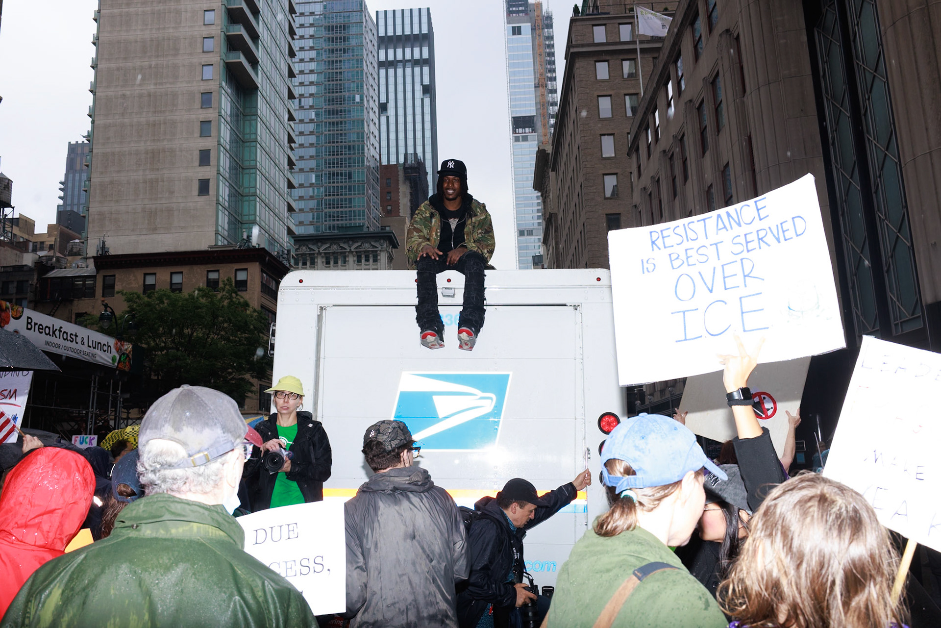 Protester Sits atop USPS Truck Holding Resistance Sign
