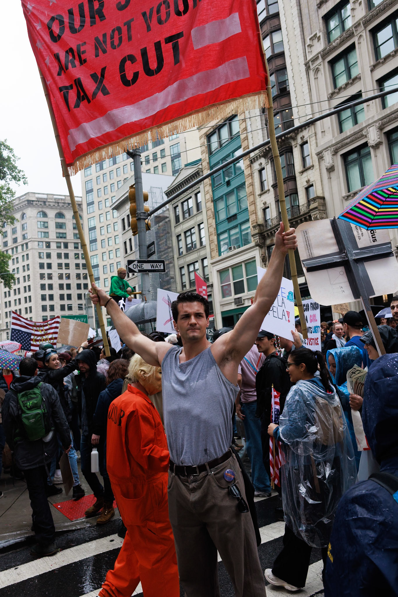 Man Holds Red Tax Cut Protest Banner in Rainy Crowd
