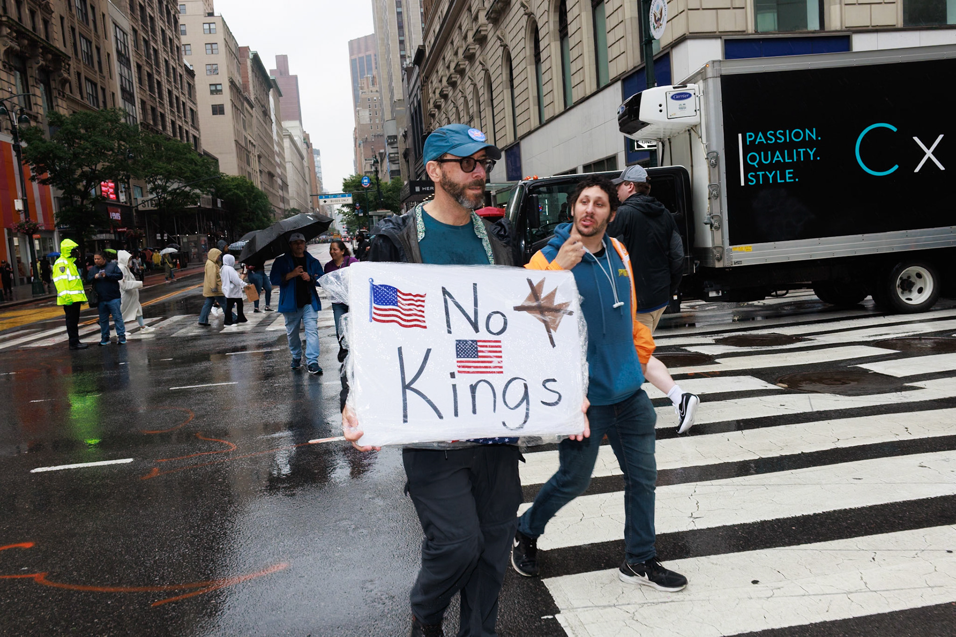 Protester Carrying No Kings Sign in Rainy City Street