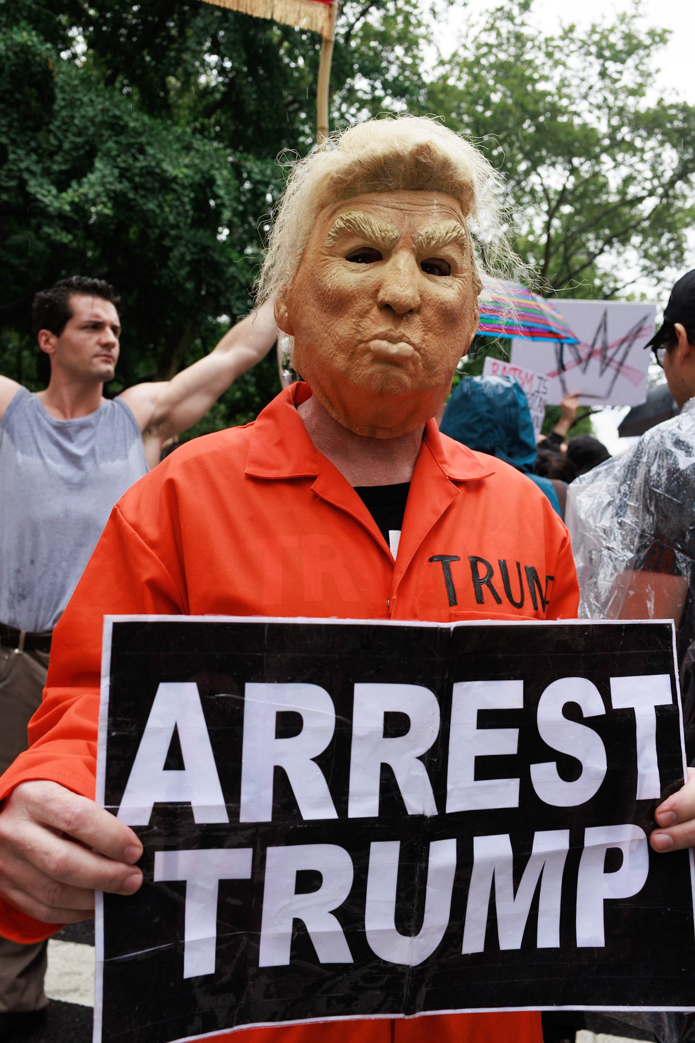 Protester in Orange Prisoner Mask Holds Arrest Sign