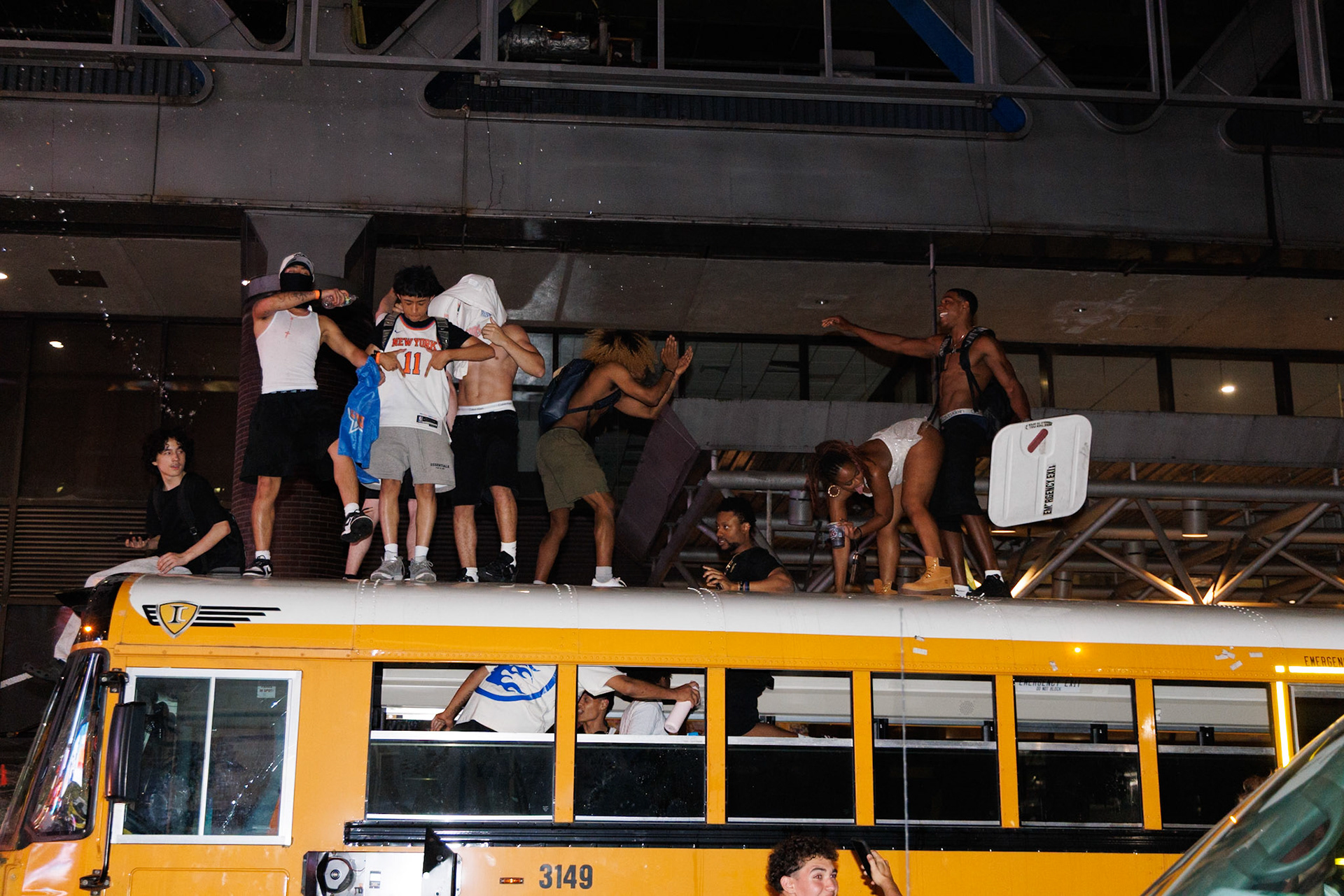 People Standing on Yellow School Bus Roof at Night