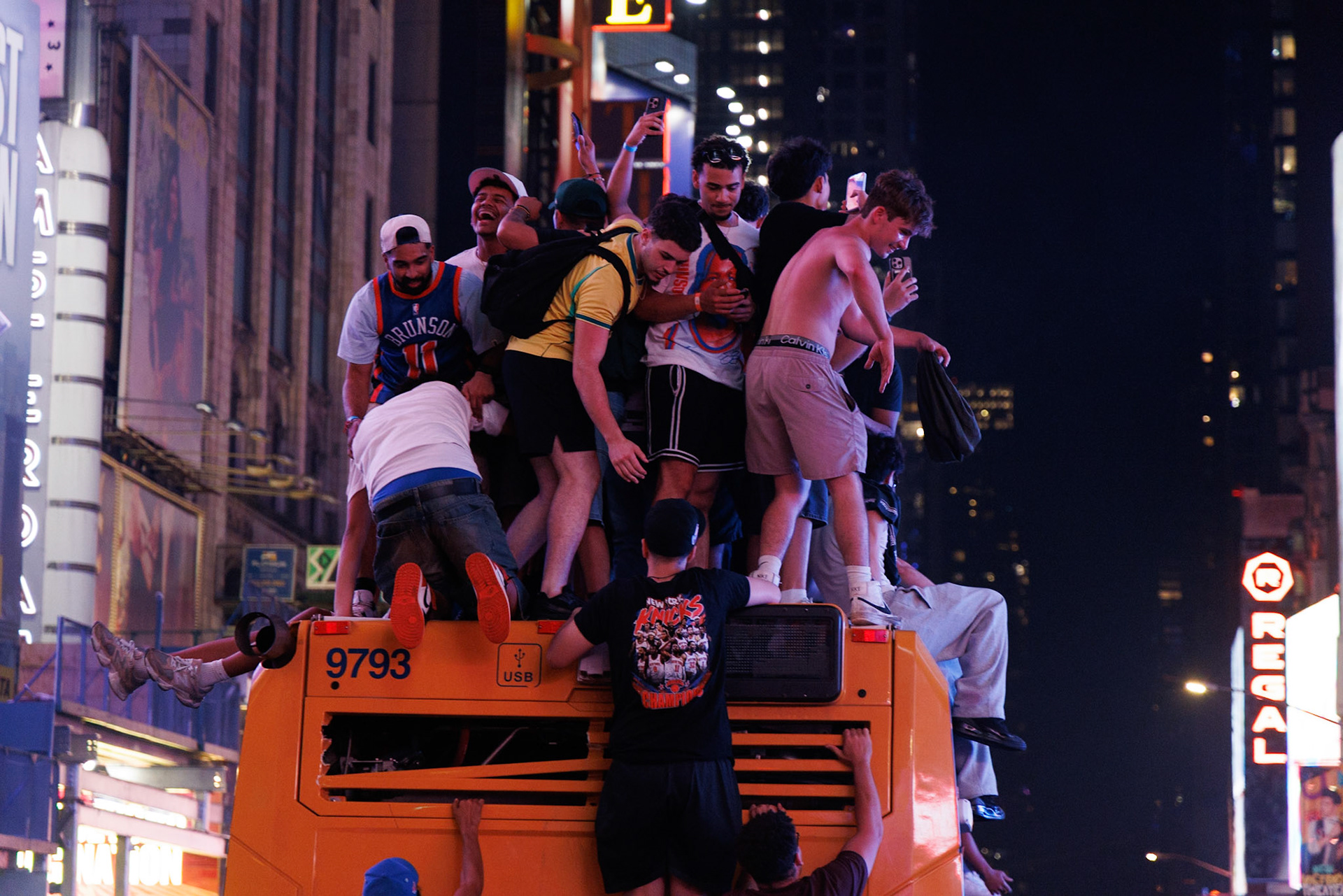Crowd Climbing Orange Bus at Night