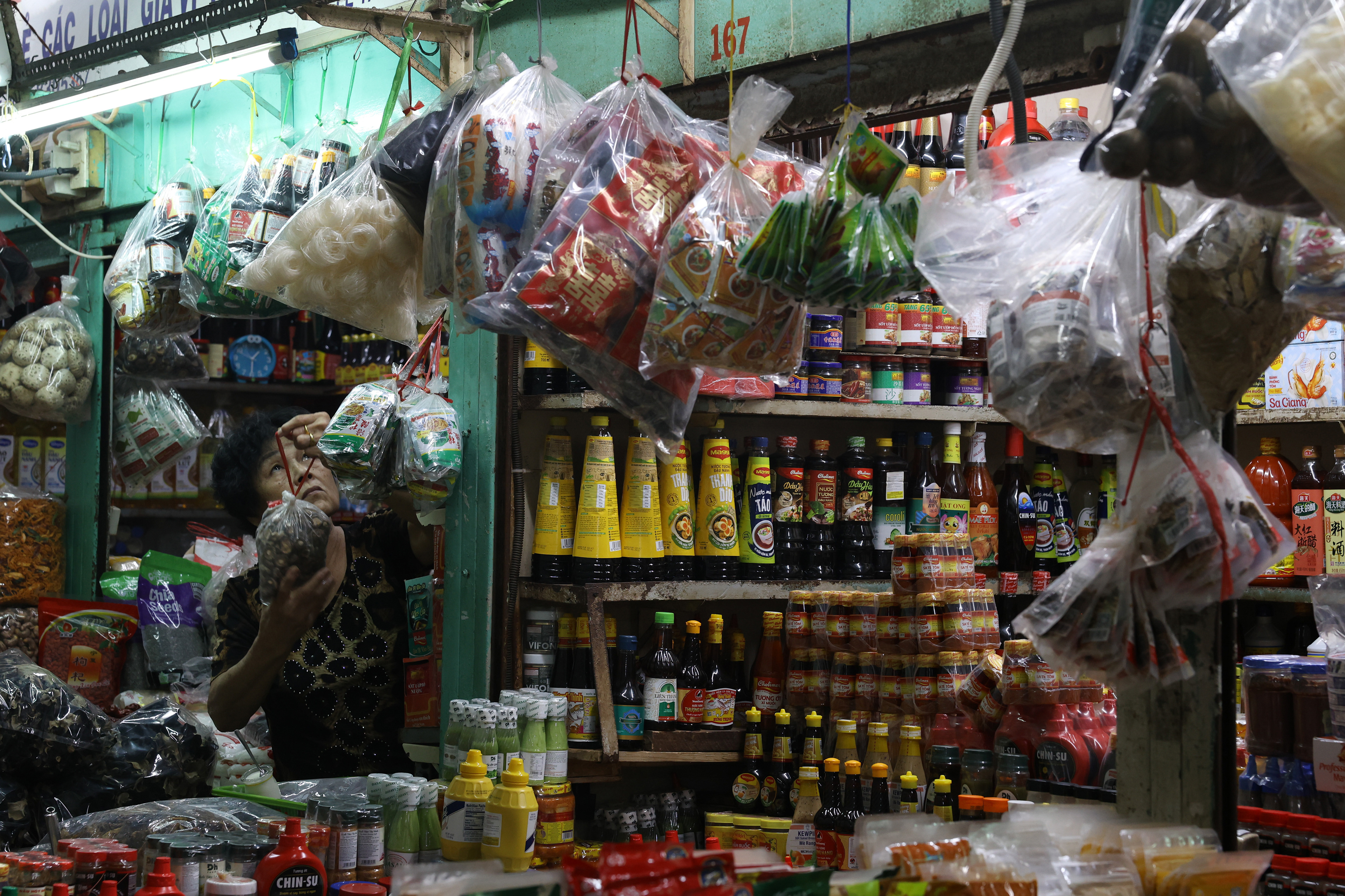 A woman hangs goods on the wall of her shop in the Binh Tay market in Ho Chi Minh City, Vietnam, on Thursday, January 2, 2025. Shops at the market sell clothing, household items, souvenirs, produce and traditional medicinal items.