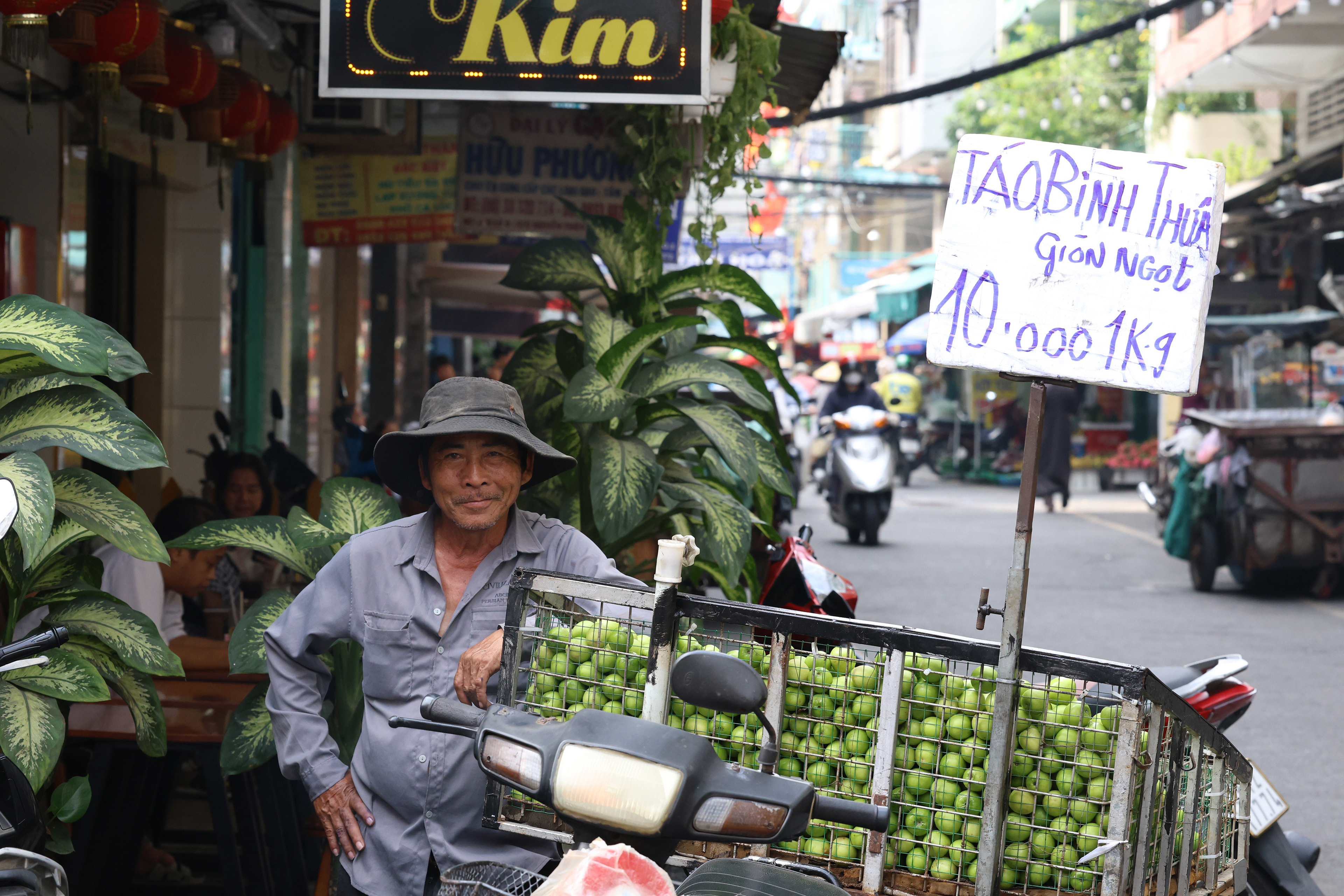 A street vendor leans on his motorbike selling Tao Ba Moi, a fruit that looks like an apple or pear but has a pit, in Ho Chi Minh City, Vietnam on Thursday, Jan. 2, 2025. He sells 2.2 lbs for 39 cents, or 1 kg for 10,000 dong.