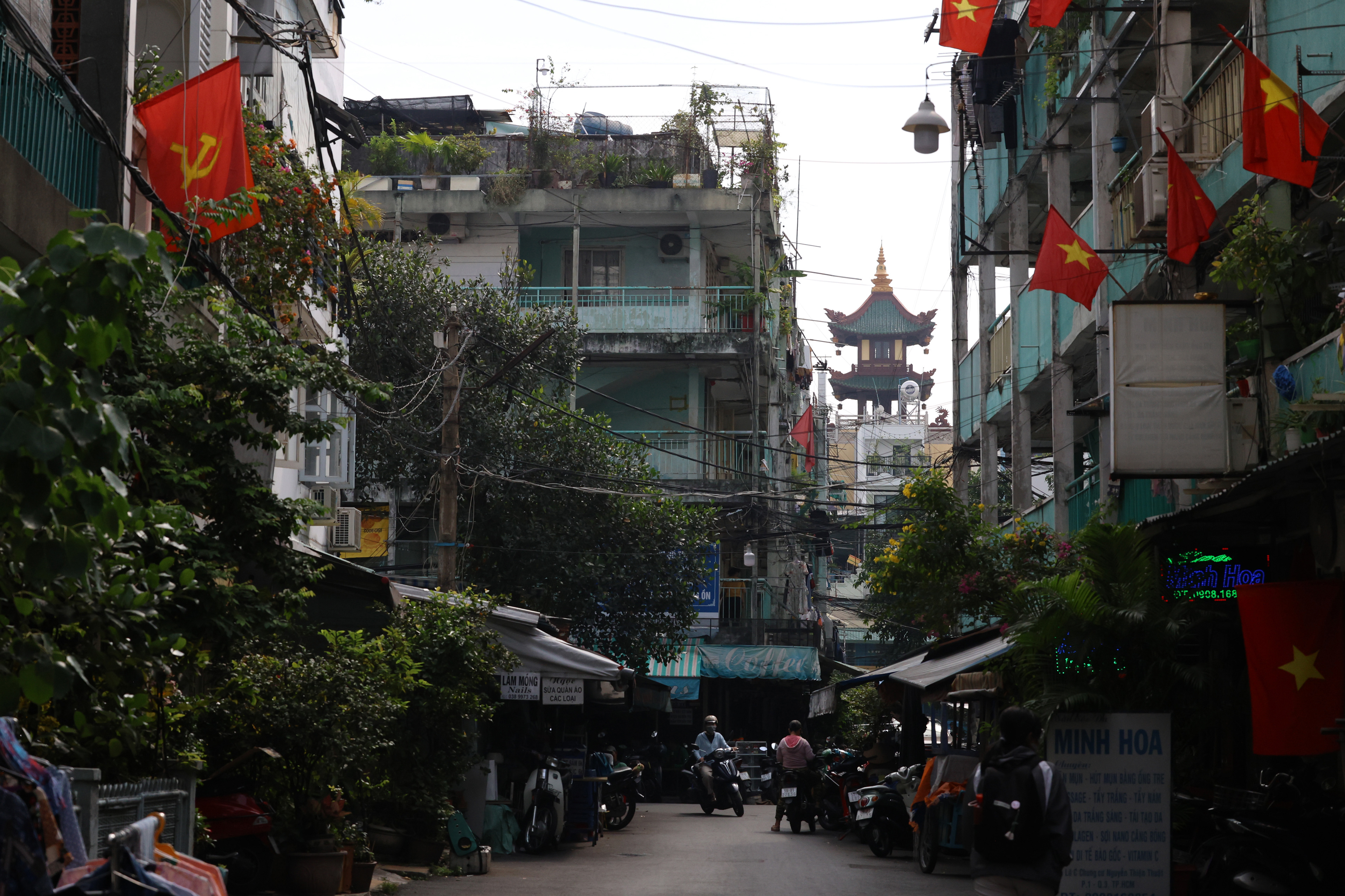 A motorcyclist turns down a street in Nguyen Thien Thuat of Ho Chi Minh City, Vietnam on Thursday, Jan. 2, 2025. The neighborhood is layered with many different parts of Vietnam’s history, featuring Chinese and Vietnamese pagodas, communist flags and the old apartments.