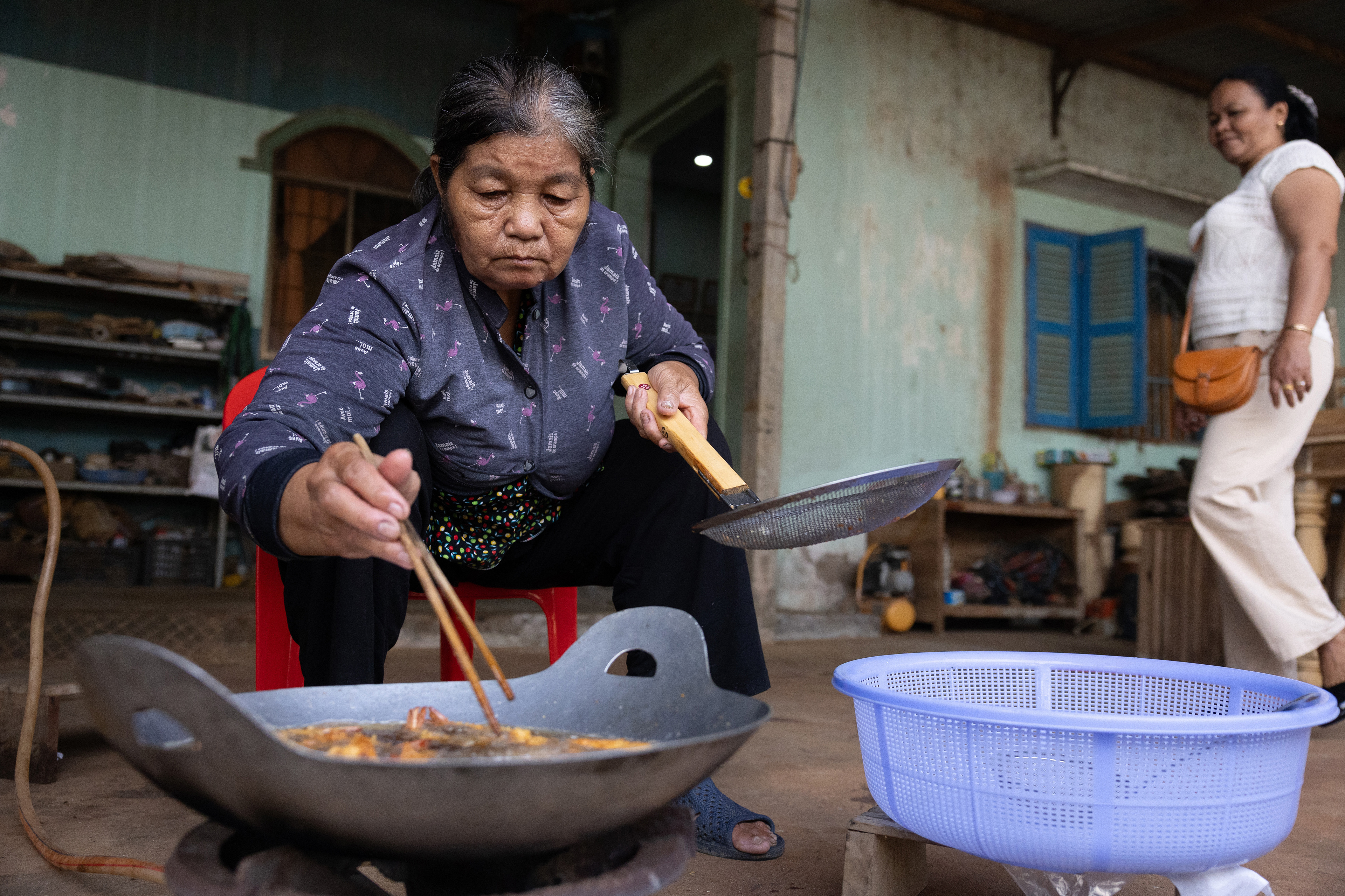 Lâm Phân, a caterer, prepares fried prawns for a child’s first birthday party in Tra Vinh, Vietnam on Saturday, January 4, 2025. The first birthday is a huge occasion for Vietnamese children, called Thôi Nôi, or “leaving the cradle,” signifying the first day of a new stage of life.