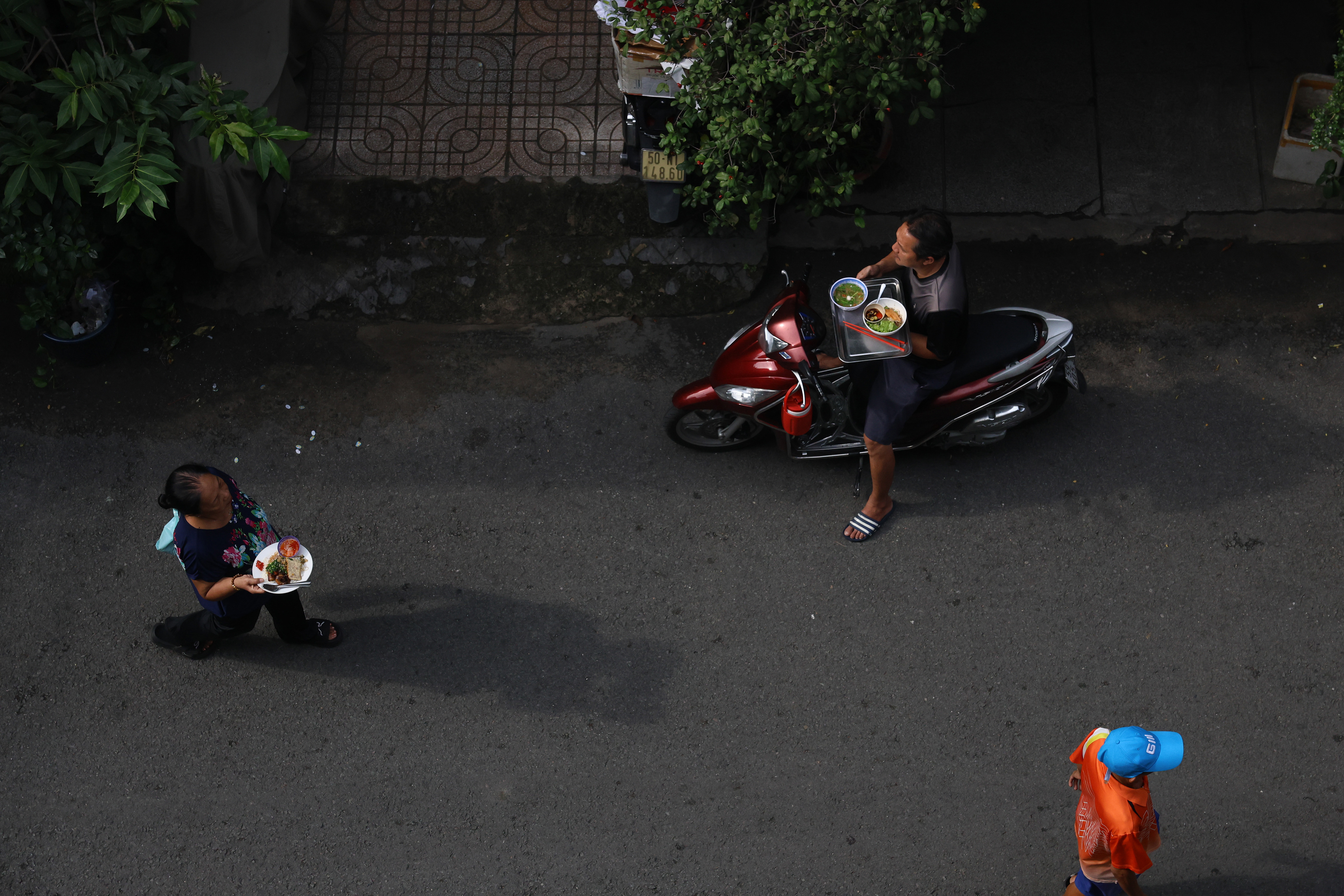 Shoppers carry food to and from vendors at Nguyen Thien Thuat in Ho Chi Minh City, Vietnam on Thursday, Jan. 2, 2025. When a purchase is made, shoppers will give vendors their phone number or home address and schedule a time for the vendor to pick up the loaned dinnerware.