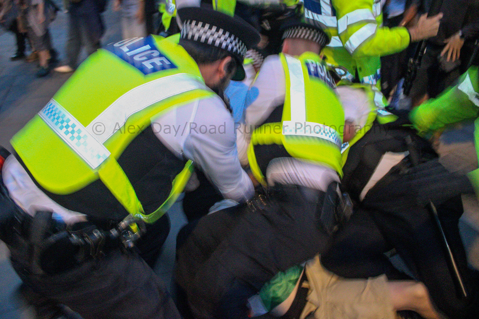 Police officers pounces on top of a protester