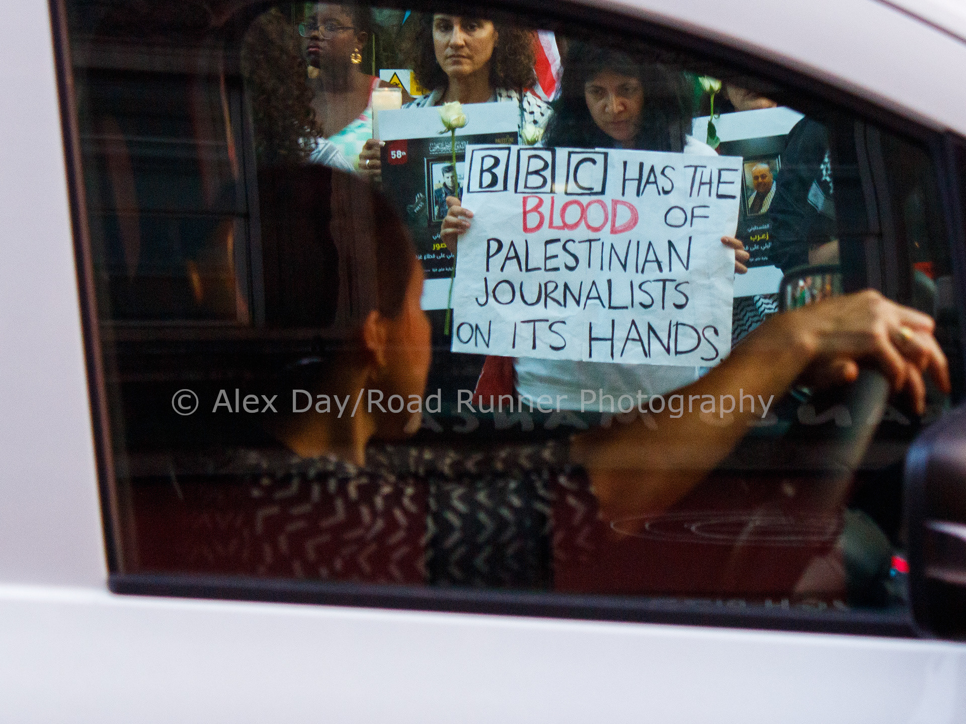 A car driver looking at a placard held by a protester
