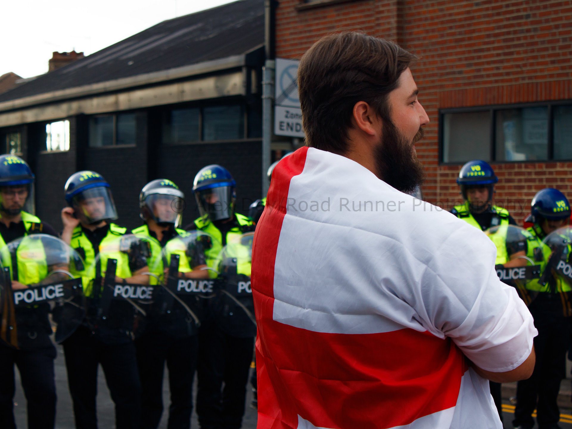 A protester in front of a line of police in riot gear 