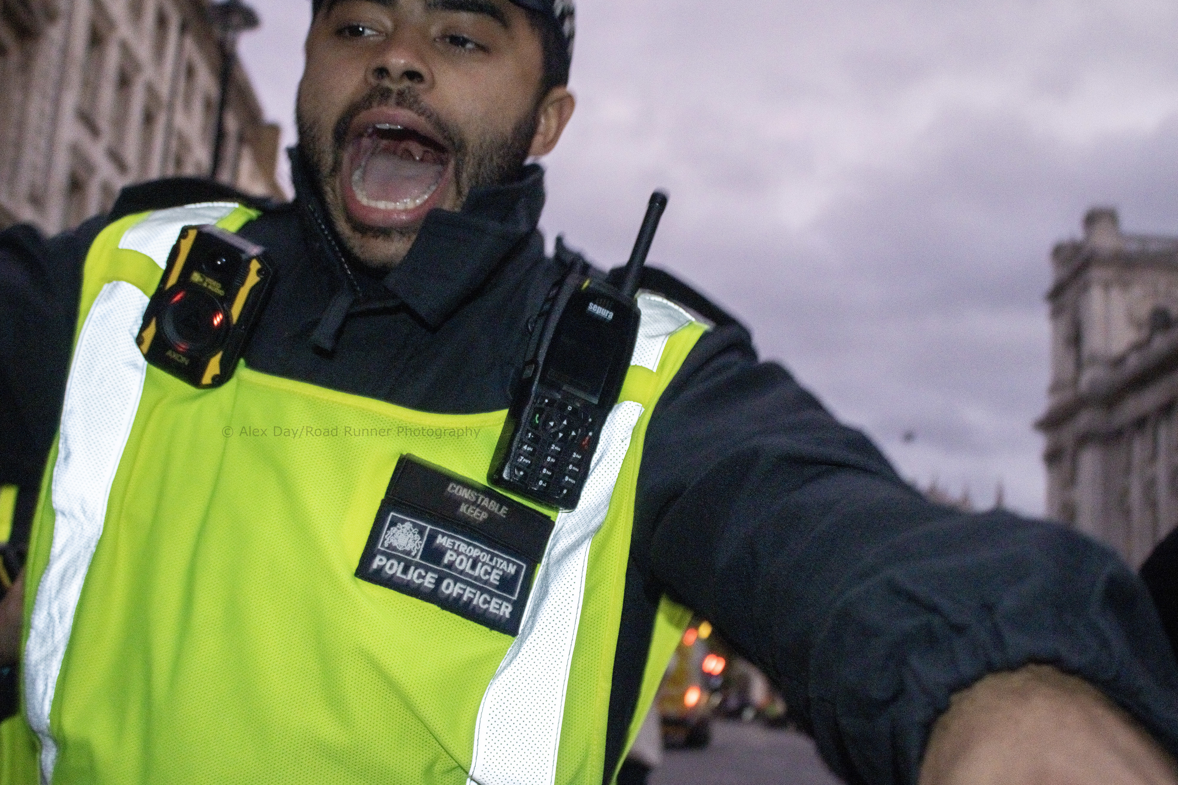 A police officer shoves protesters (and press) back
