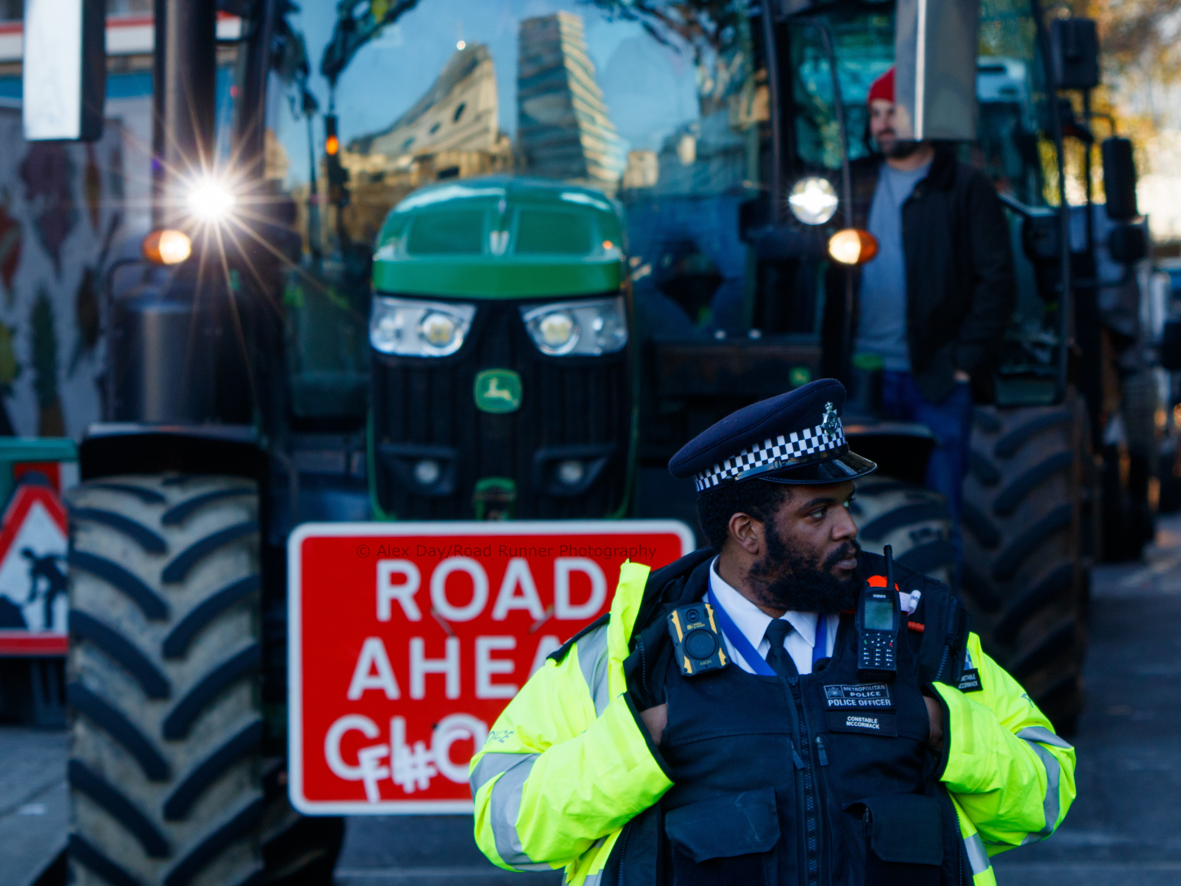 Police standing in front of a tractor at a protest 