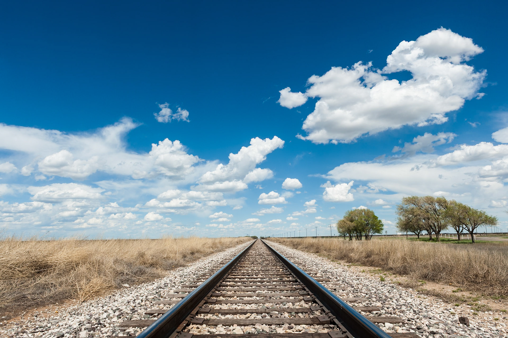 Rail Road going to infinity under a blue sky with white Clouds in New Mexico, USA