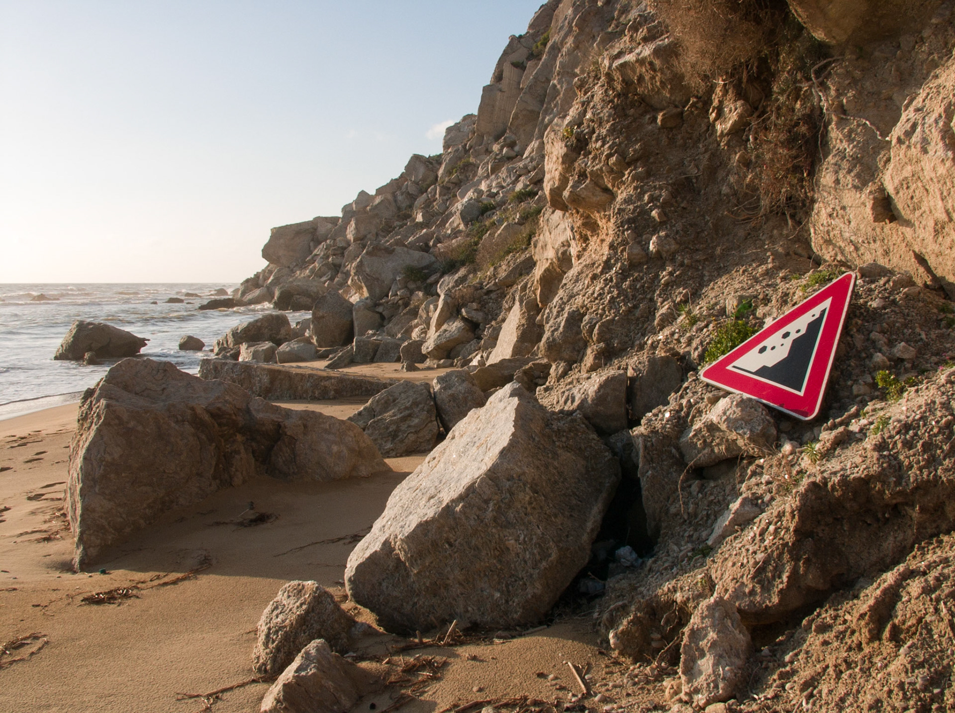 Danger falling rocks sign between falling rocks at the Beach of Marina Siculiana