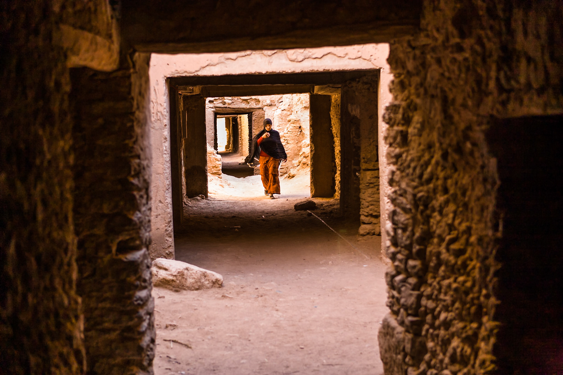 MOROCCO, P Woman walk in a passage at Kasbah of Tissinnt at route N20