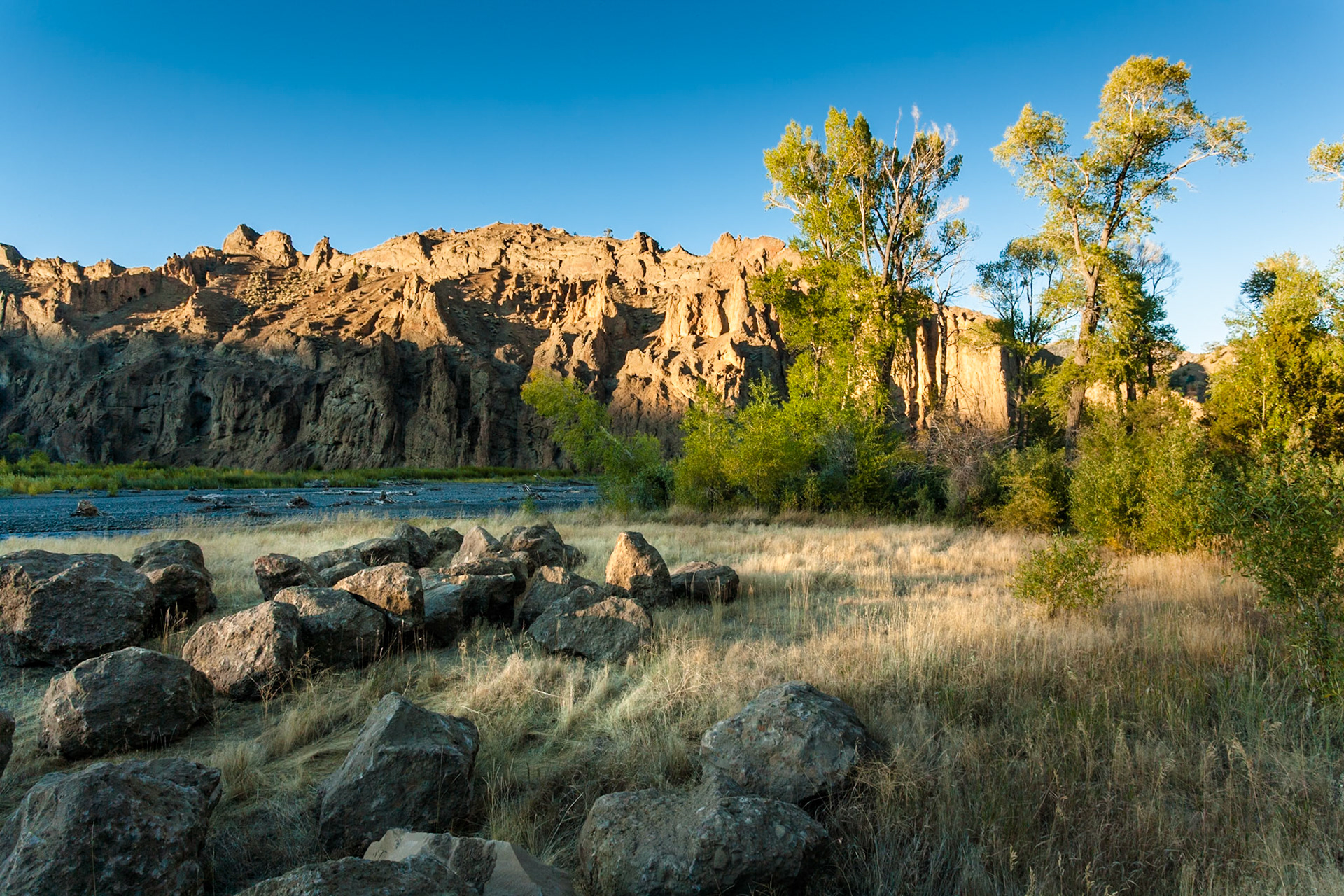 Sunset at Shoshone River between rocks and colored trees at Wapiti Valley, Wyoming, USA