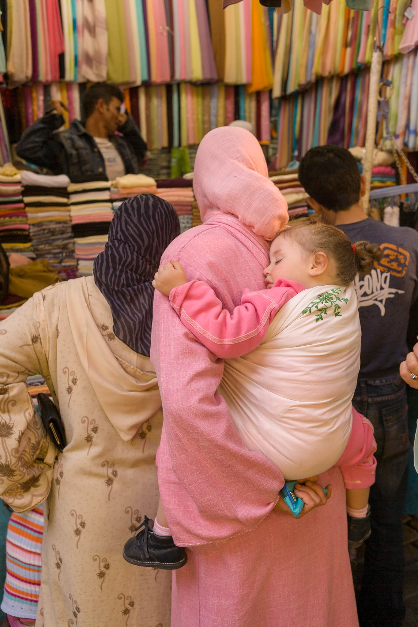 Baby sleeping at back of her mother at souk near Place Djamaa El Fna at Marrakech