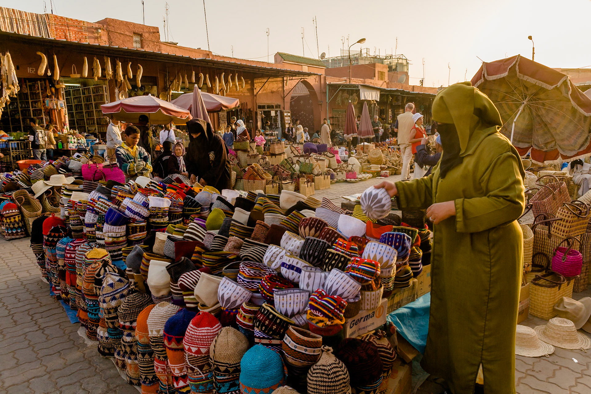 Woman is looking at a cap at the Shops at sunset at souk near Place Djamaa El Fna at Marrakech