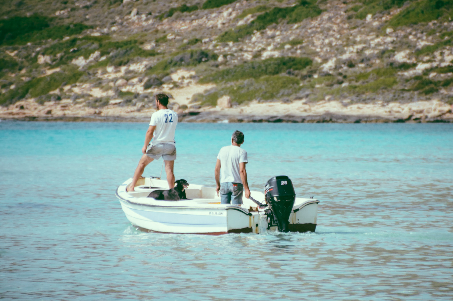 Two men and a dog riding a boat at Balos Beach, Chania, Crete