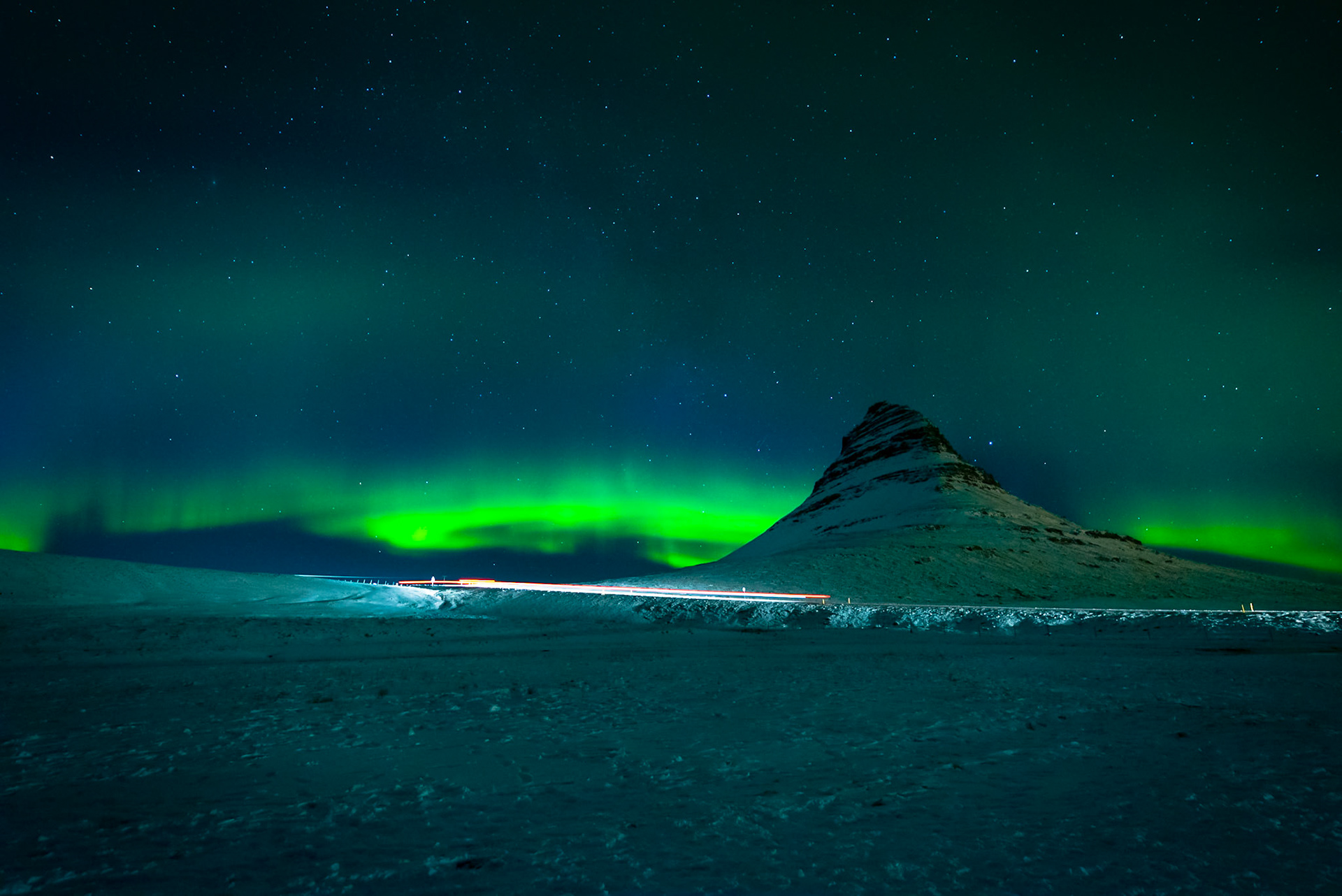 Northern lights and car trails with Kirkjufell in the background in Iceland