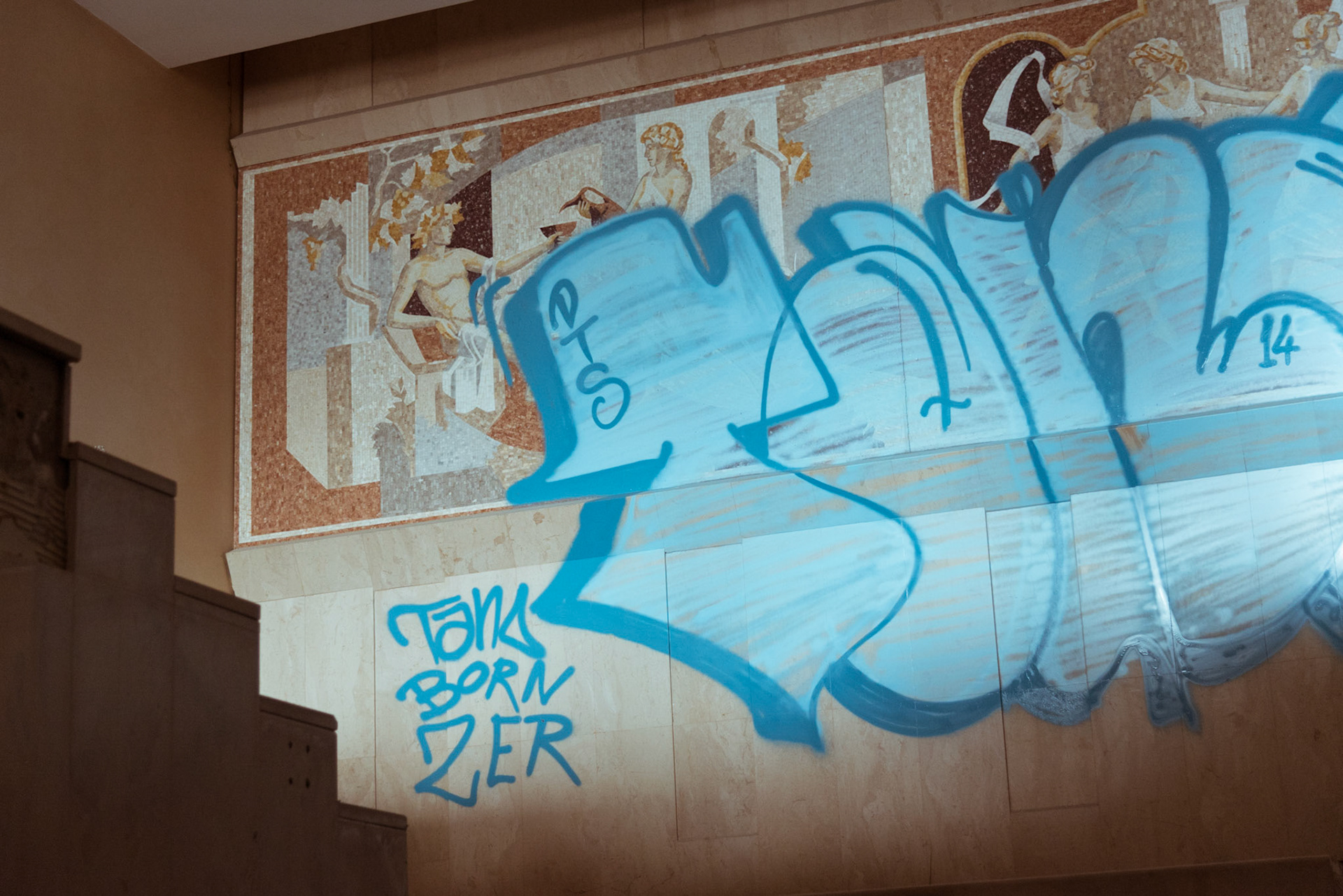 Street art over the mosaic of the main staircase of the abandoned hotel